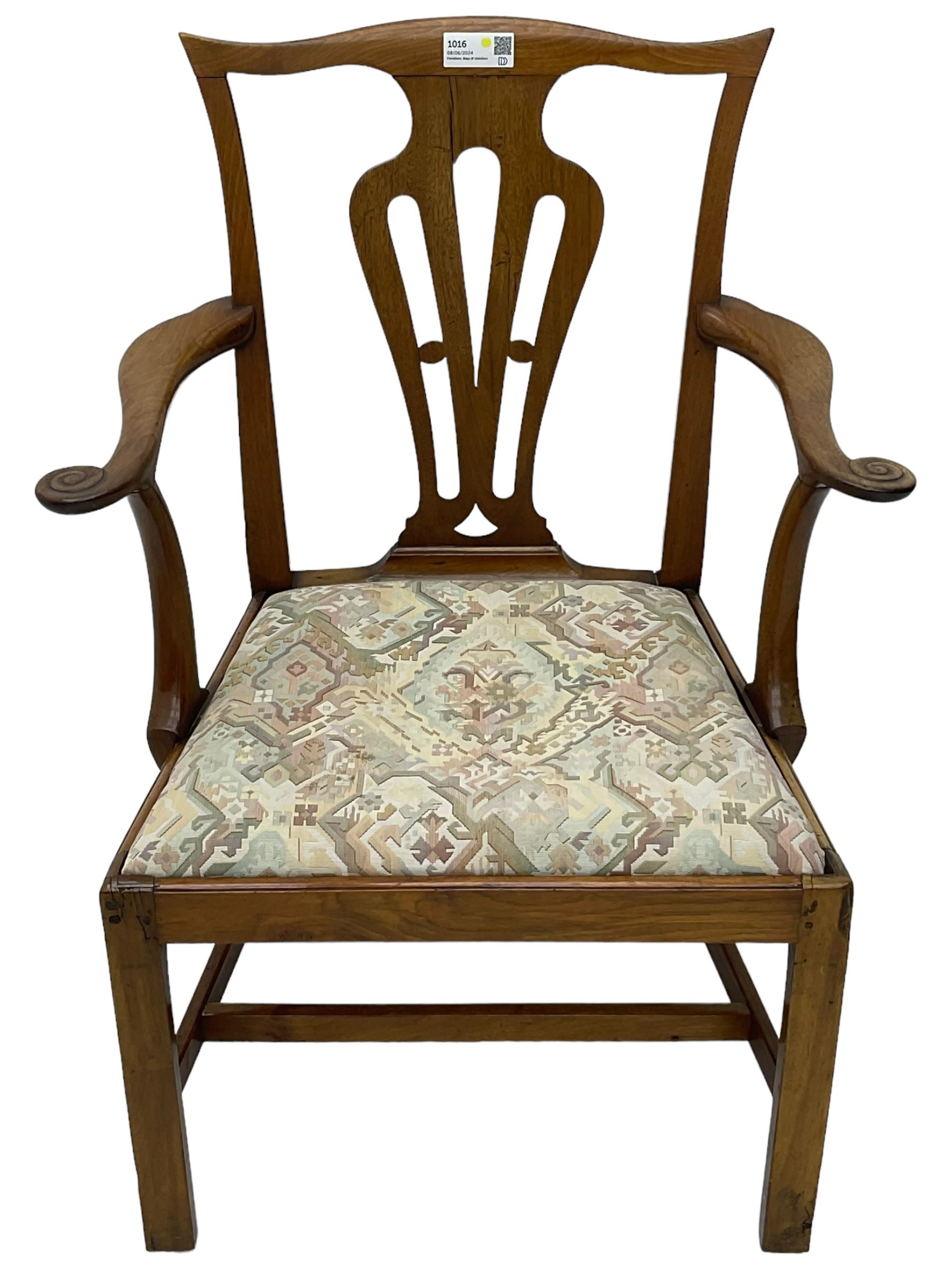 George III walnut elbow chair, shaped cresting rail over shaped pierced splat, the shaped arms with scroll carved terminals, upholstered drop in seat, on square chamfered supports united by plain stretchers 