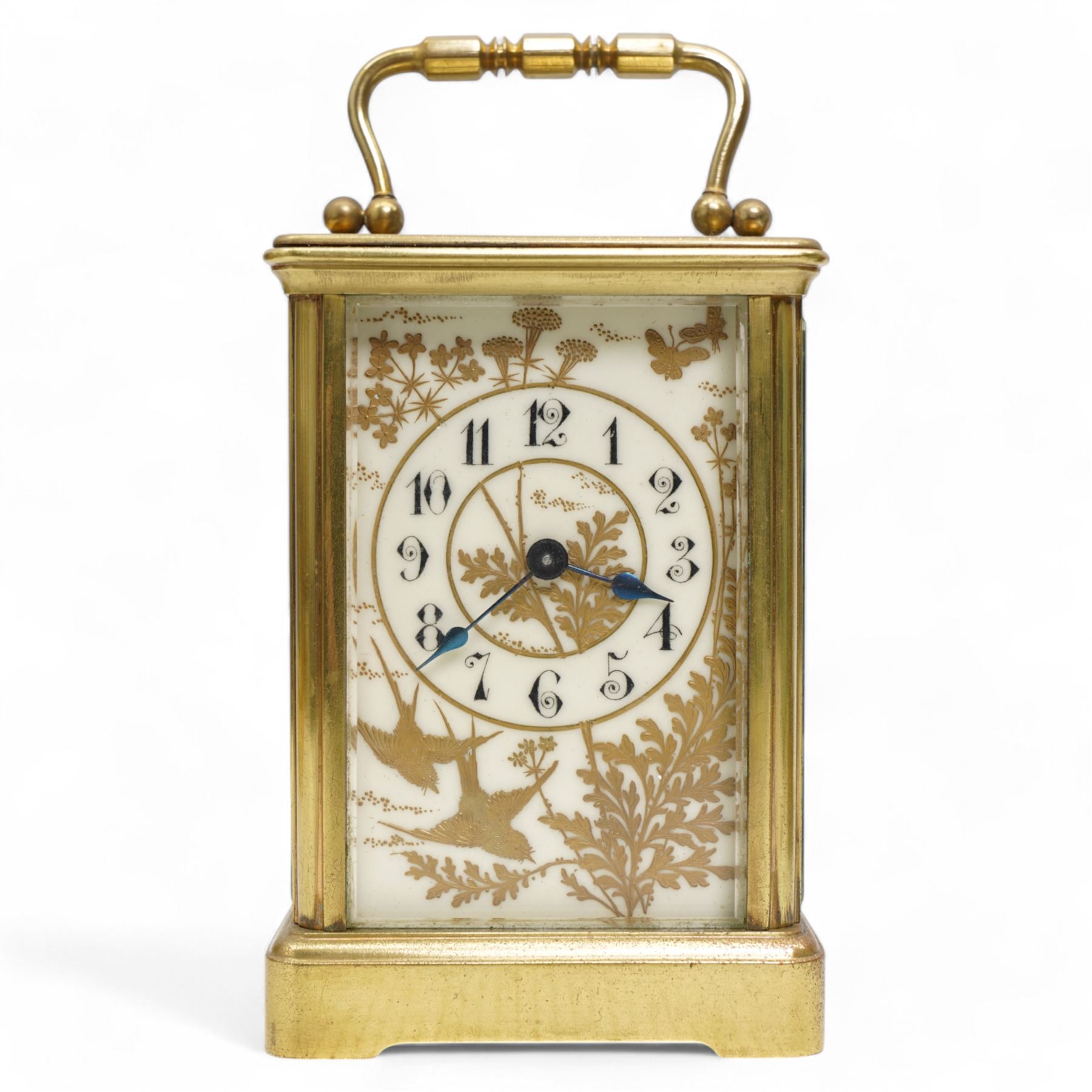 French - Early 20th century 8-day brass carriage clock in a corniche case, with rectangular glazed  panels and an oval viewing glass to the top, enamel dial with raised and gilded decoration in the form of swallows, leaves and flora, contrasting Arabic numerals and steel spade hands, with a cylinder platform escapement, wound and set from the rear. With key.