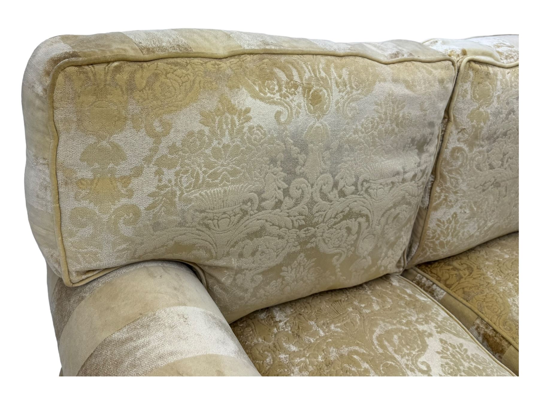 Contemporary two-seat sofa, upholstered in damask fabric with a pale gold floral pattern, rolled arms, loose back and seat cushions, on matching skirted base with concealed castors