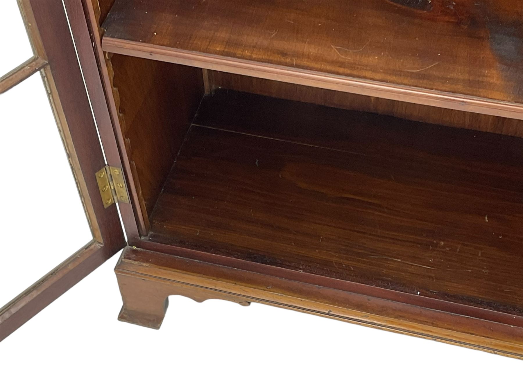 Early 20th century mahogany bookcase, projecting dentil cornice over blind fretwork frieze, enclosed by two astragal glazed doors, on shaped bracket feet 