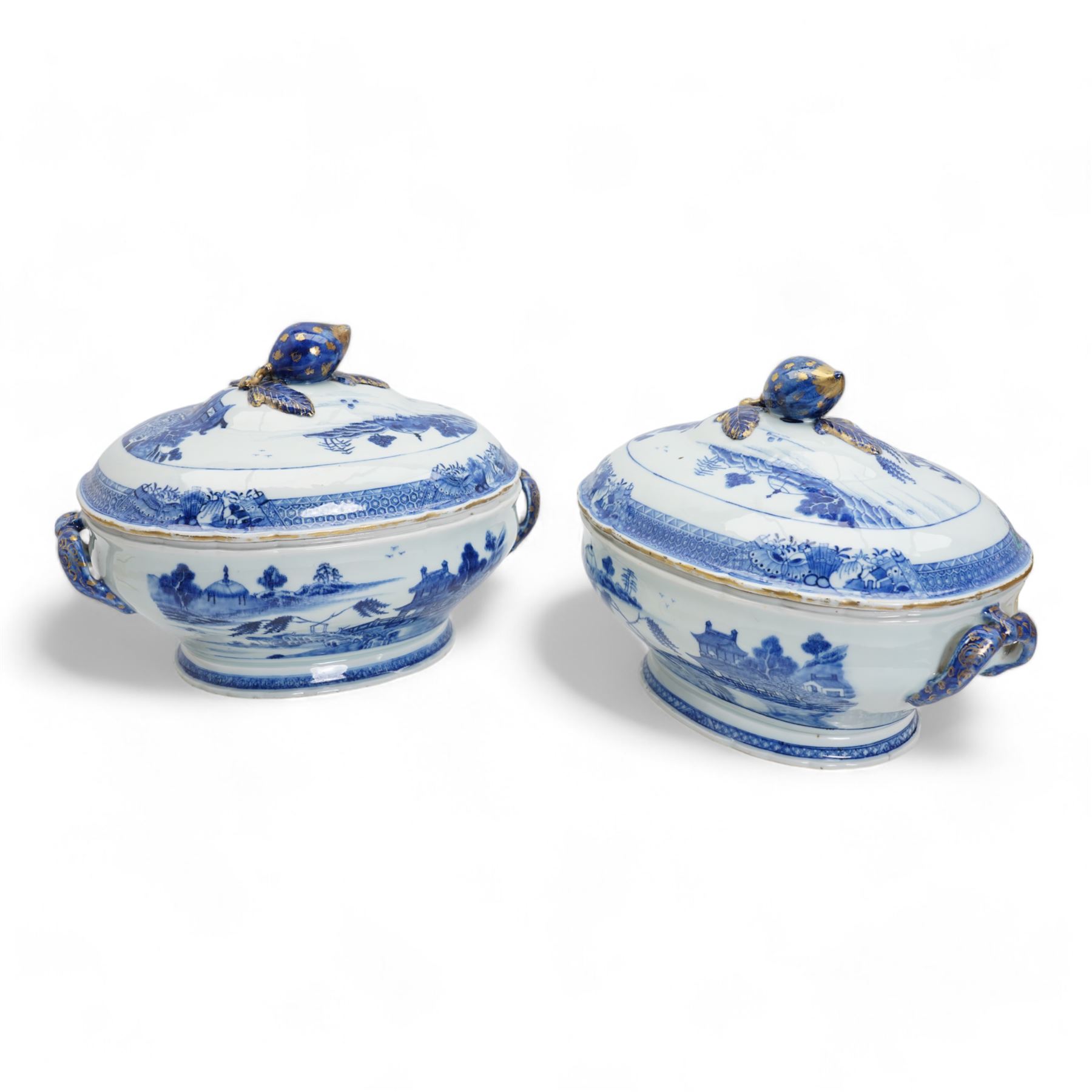 Pair of 18th century Chinese Export blue and white parcel gilt lidded tureens, each of twin handled oval form, decorated with buildings and landscape scenes within geometric and cell borders, with fruit finials, L33cm x H26cm approx.