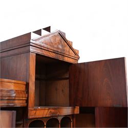 19th century Biedermeier figured mahogany cylinder bureau cabinet, the raised super structure with stepped pointed pediment over hidden cupboard and hinged fall front, the interior fitted with pigeonholes and secret drawers behind rusticated inlay, curved flanking cupboards fitted with internal drawers, the cylinder top opens to reveal small drawers, document divisions and secret compartments, sliding desk with central hinged writing surface, inlaid with satinwood bands and draped festoons, fitted with three long drawers, on bracket feet