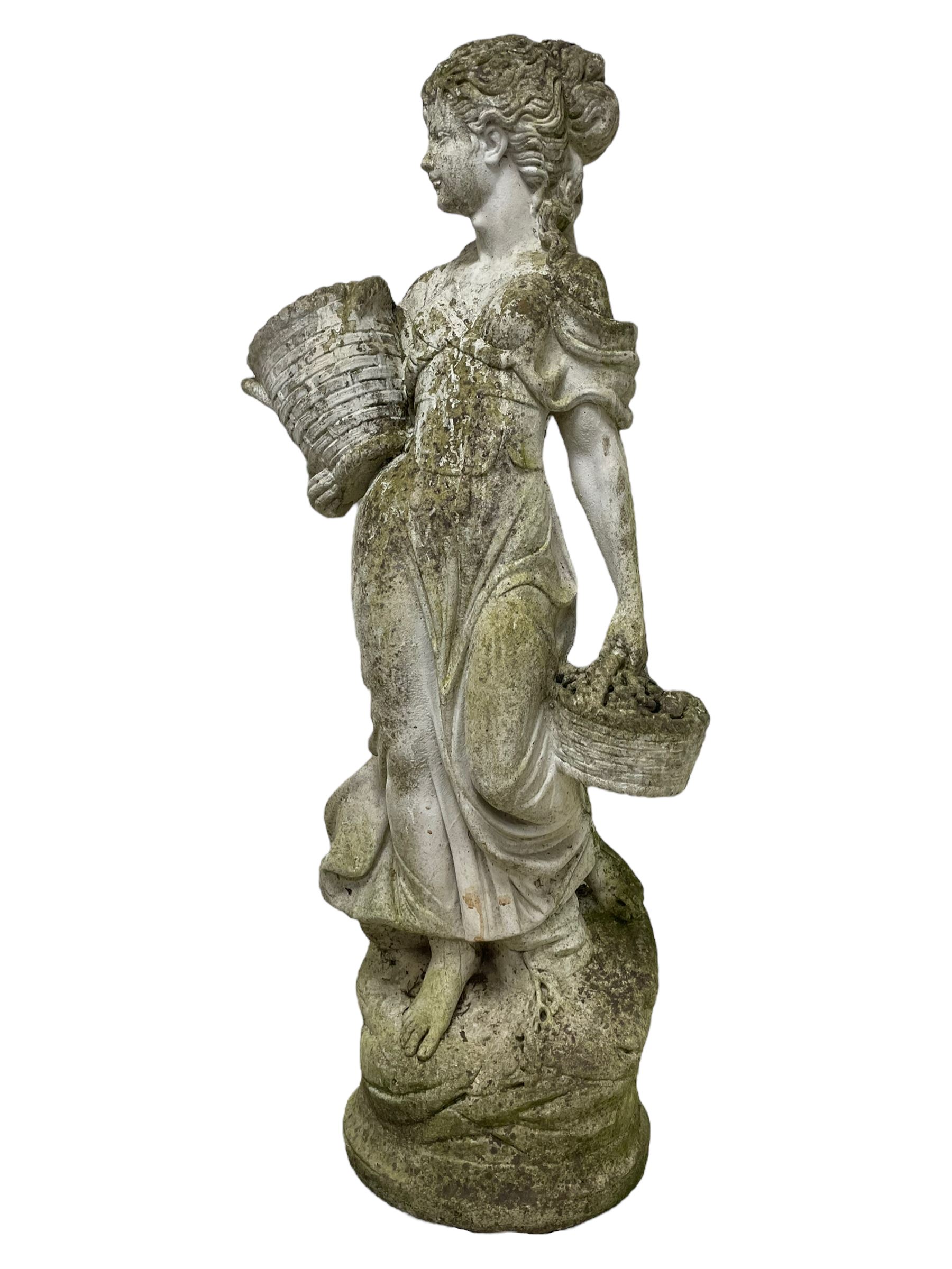 Weathered and painted cast stone garden statue, in the form of an Italian maiden carrying baskets with gathered flora and berries, on a shaped ovoid base