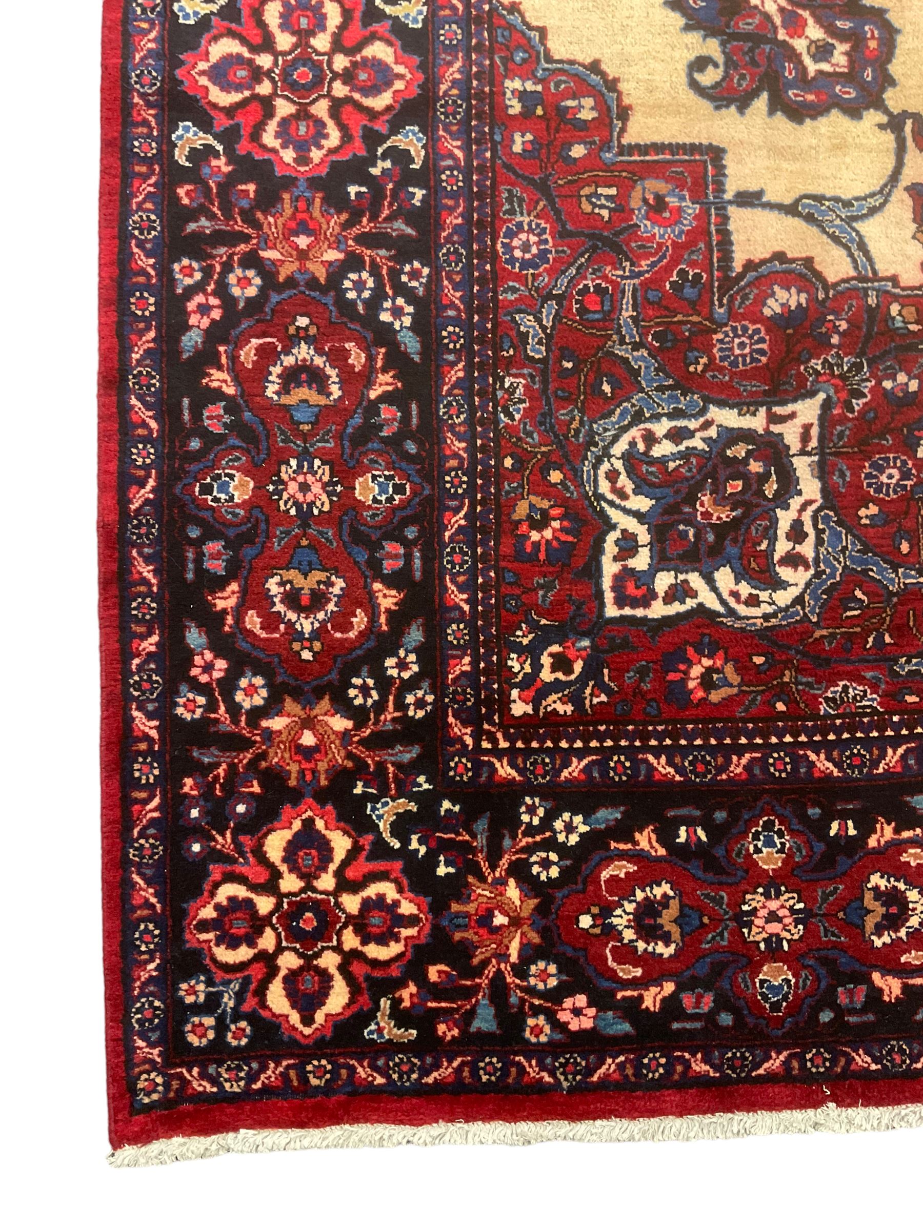 North East Persian Meshed carpet, the field with large central medallion decorated with stylised plant motifs, the field surrounded by panels, medallions and spandrels decorated with floral motifs, indigo ground border with overall floral design 