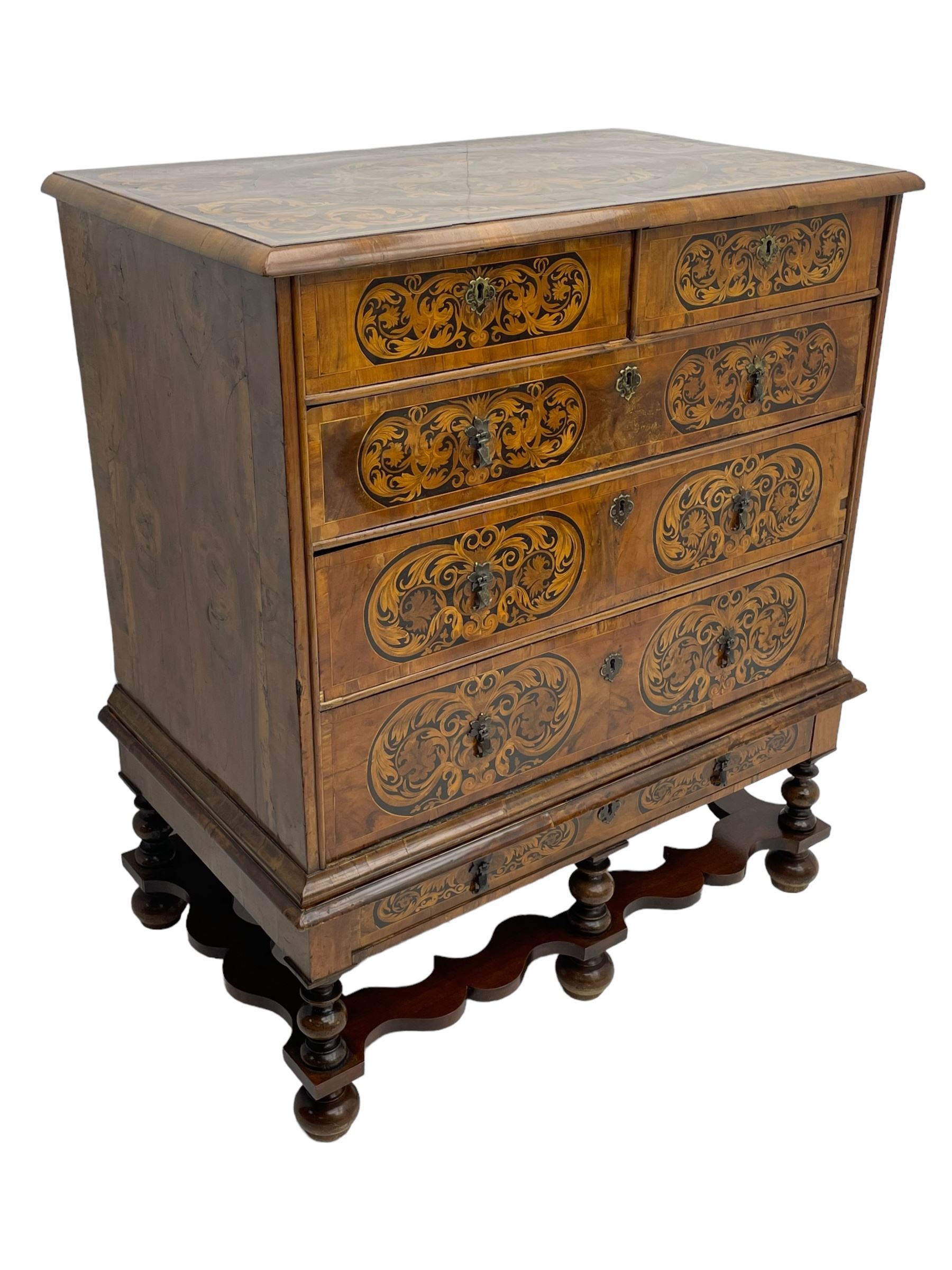 18th century inlaid walnut chest on stand, ovolo-moulded rectangular top inlaid with ebony panels each decorated with scrolling foliage, flower heads and birds, fitted with two short over three long drawers, the drawer fronts decorated with ebony panels enclosing curled leaf inlays, the base fitted with single drawer on turned supports united by waved stretchers, on turned bun feet 