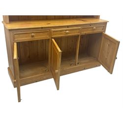 Traditional design waxed pine dresser, upper section with moulded cornice over scalloped frieze, fitted with two open shelves and four drawers, lower section with three drawers over three panelled cupboards, on plinth base