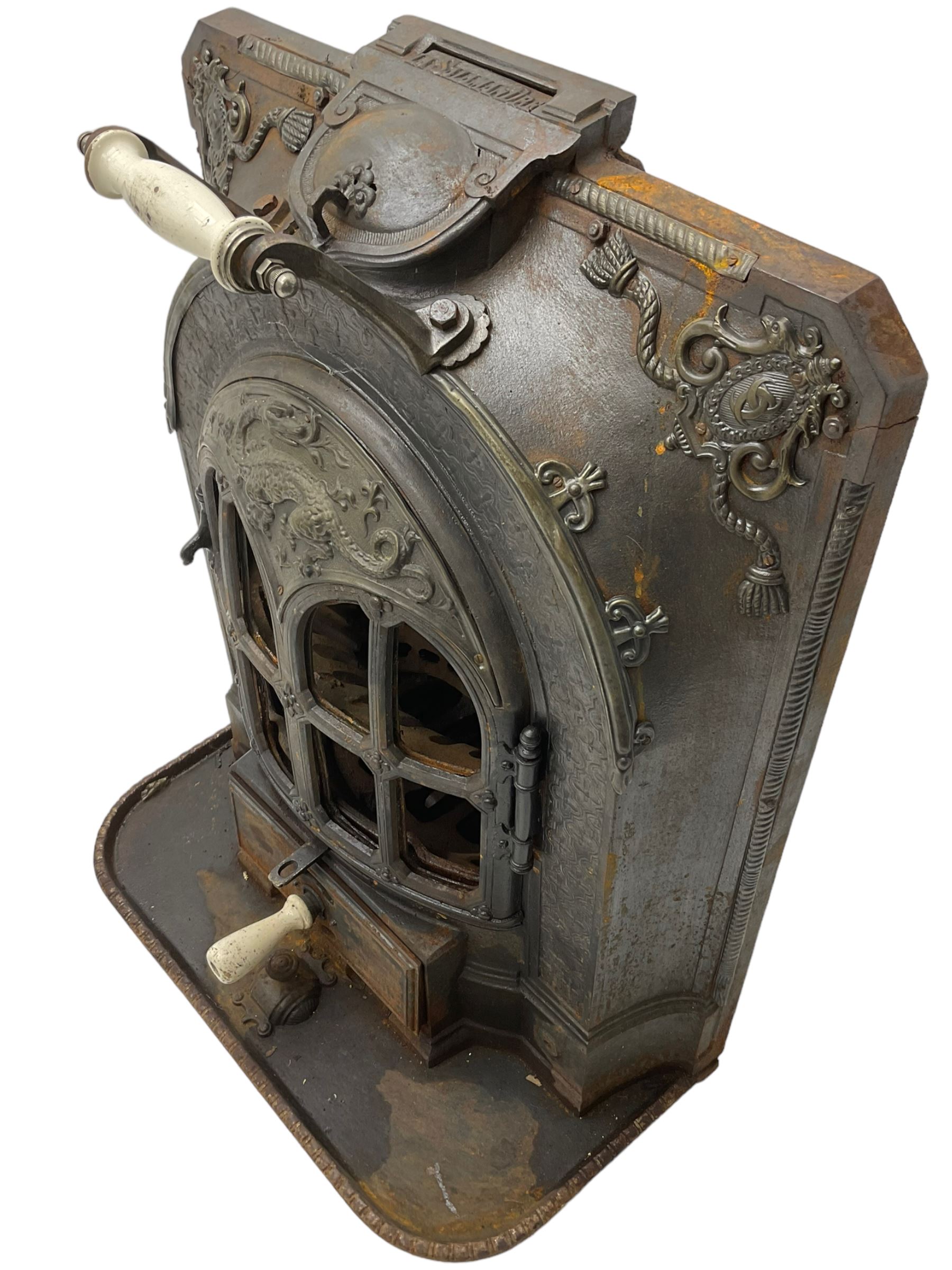 La Salamandre - early 20th century cast iron wood burning stove, decorated with salamander and cartouche motifs, fitted with porcelain handle, on rear castors 