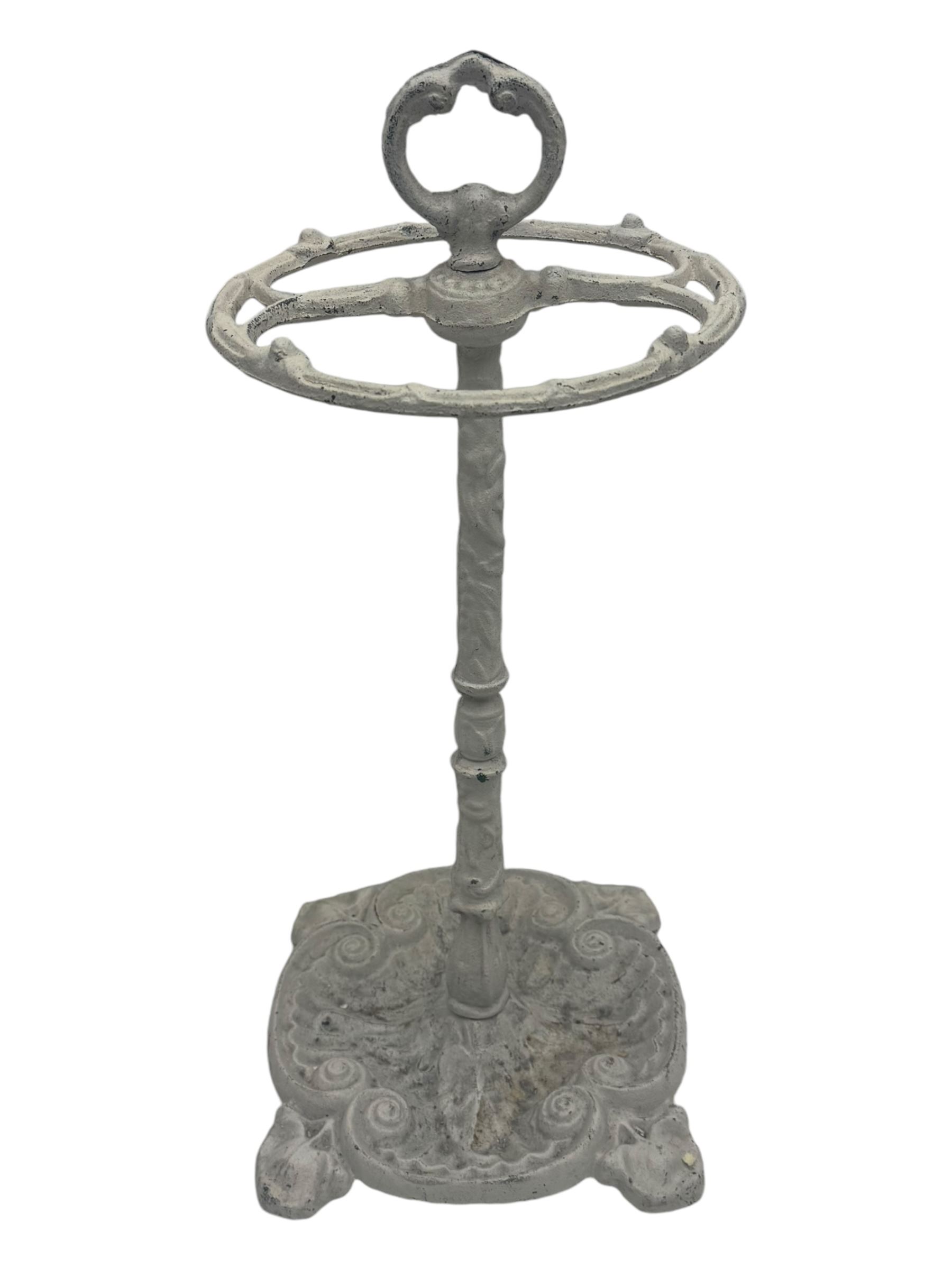 Victorian design cast iron umbrella stand, ornate stem on shell C-scroll base; together with a collection of walking sticks including a silver tipped cane 