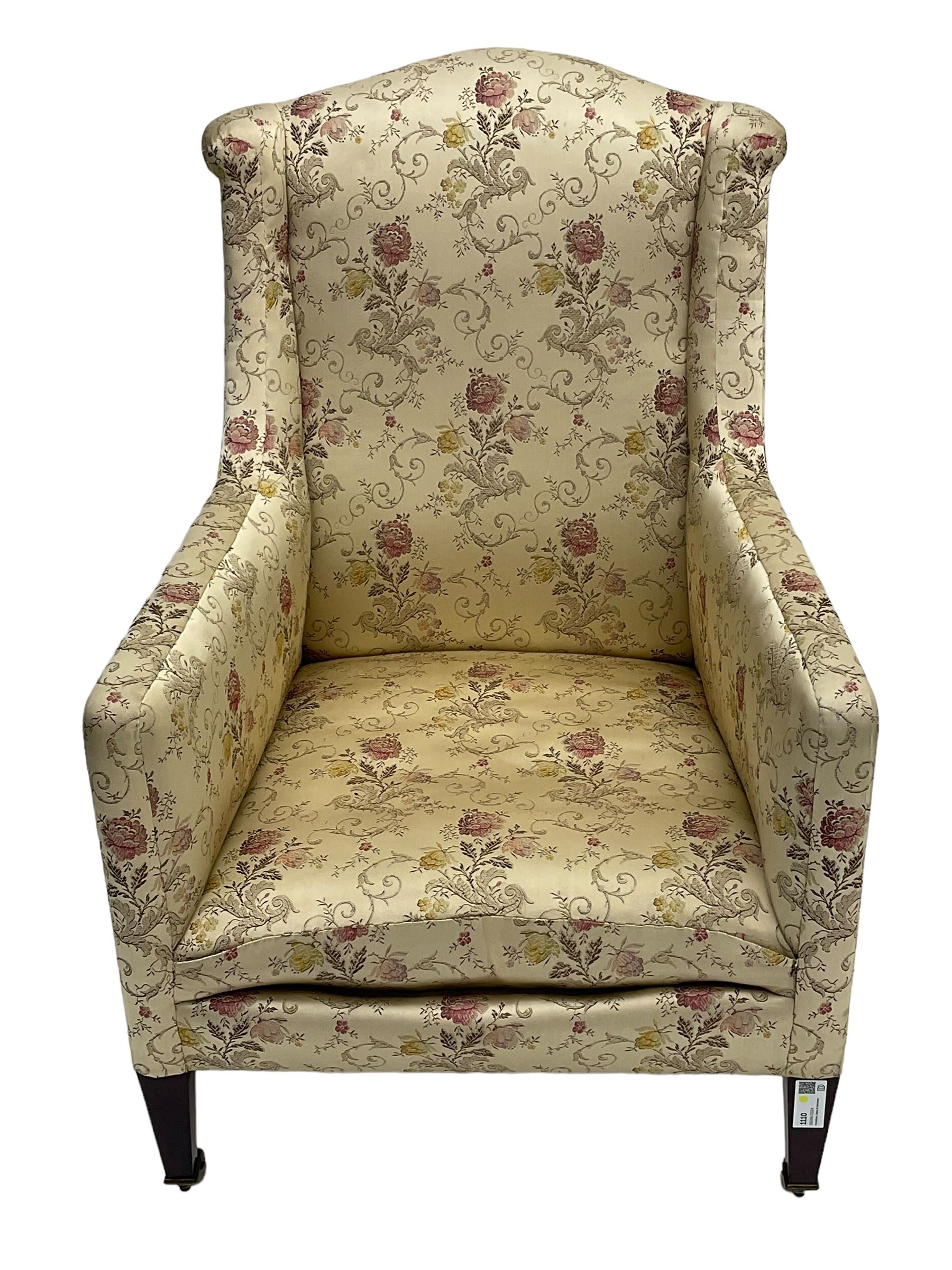 Edwardian hardwood-framed armchair, upholstered in floral pattern fabric, on square tapering front supports, brass and ceramic castors 