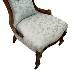 Victorian walnut nursing chair, the curved cresting rail carved with central cartouche and scroll leaves, upholstered in pale blue fabric decorated with trailing floral design, on cabriole front feet 