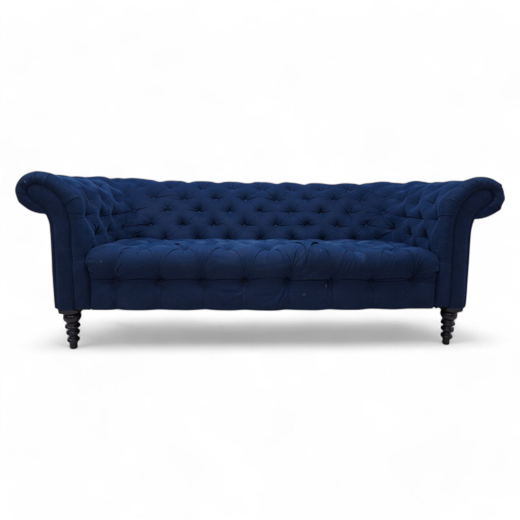 Chesterfield three-seat sofa, traditional shape with rolled arms, upholstered in deep blue buttoned fabric, on black finish turned front feet 