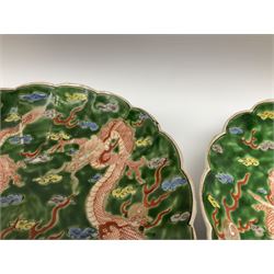 Pair of Japanese Meiji period plates, of circular form with lobed rims, each decorated with two red three clawed dragons chasing flaming pears amidst auspicious clouds, upon a green awaji type glazed ground, each with character mark beneath, D24.5cm