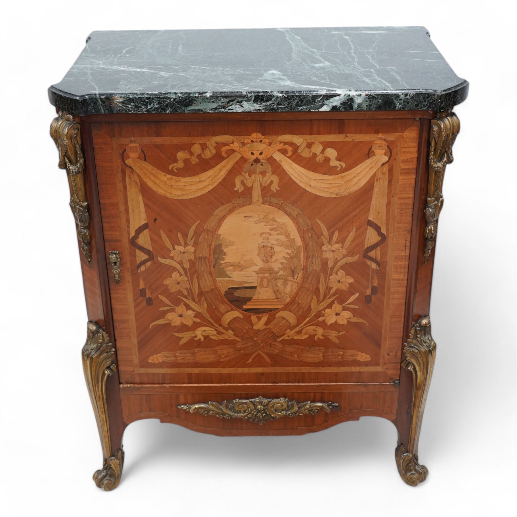 20th century French Kingwood and gilt metal mounted side cabinet, moulded green variegated marble top over single cupboard, enclosed by marquetry inlaid single door, the oval panel depicting urn and bridge in garden landscape, surrounded by fruiting laurel wreath and enclosed by draped linen swags, decorated with trailing leafy branches and flower heads, canted corners with scroll and acanthus leaf cast mounts decorated with laurel swags, curled acanthus leaf lower mounts terminating to scrolled terminal caps, the interior fitted with single shelf 