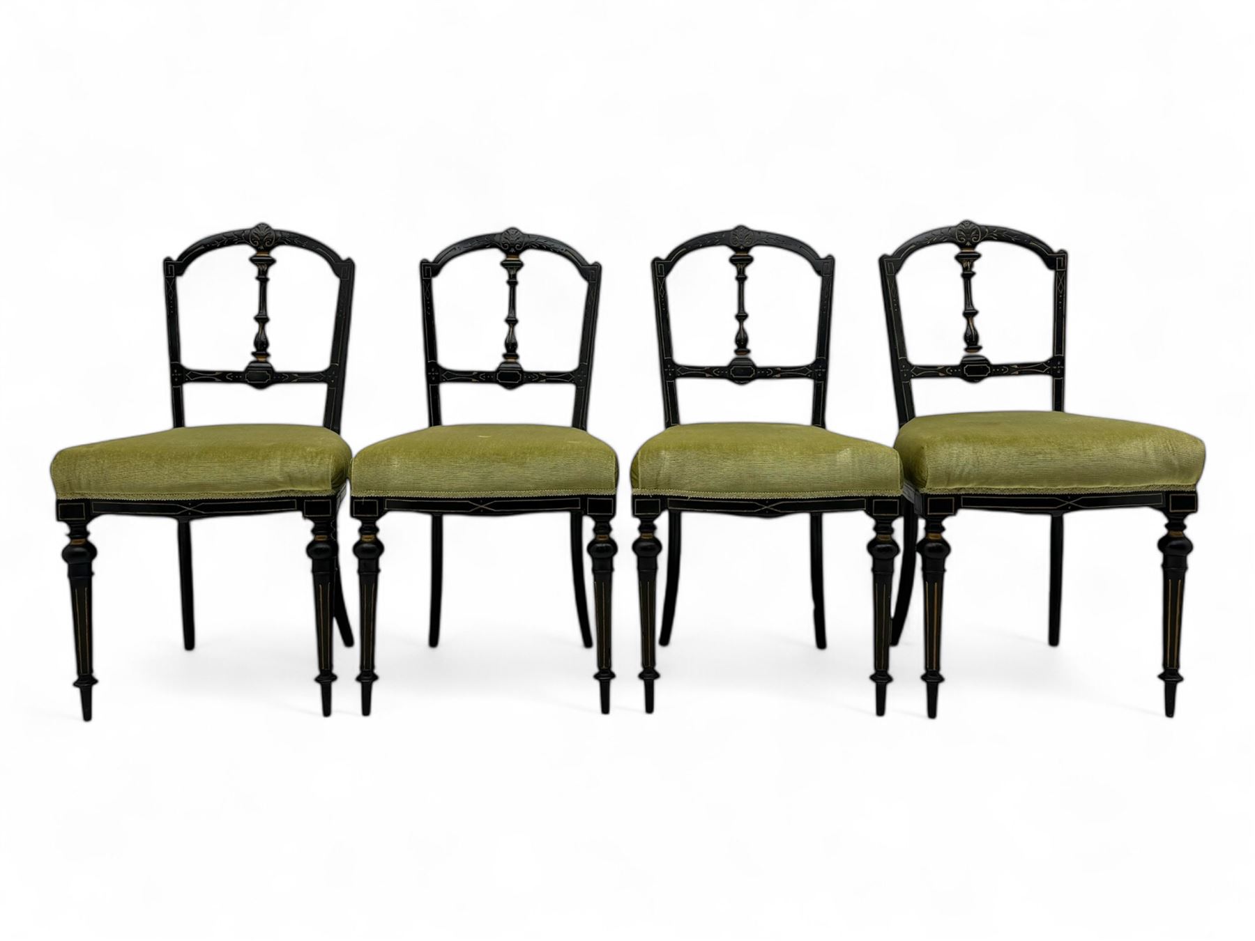 Set of four late Victorian ebonised dining chairs, decorated with carved and gilt foliate decoration, upholstered seats, on turned and fluted front supports 