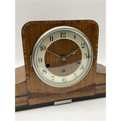 A 1930’s eight-day three train art deco Westminster chiming mantle clock with a Haller & Benzing (German) movement chiming the quarters on five underslung gong rods, silver effect chapter ring with upright Arabic numerals and minute track, strike/silent lever, chrome spun bezel with a convex glass, pierced chrome hands, walnut veneered case inlaid with cross banding and inlaid with amboyna and ebony.
With pendulum.
Haller & Benzing were a short-lived firm of German clockmakers with a factory in Villingen-Schwenningen from 1918 to 1929, mainly known for producing industrial clocks, their domestic clocks are not as well known. 
