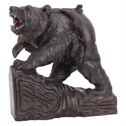 20th century Black Forest carving of a bear carrying a fish upon its back, with open mouth, painted tongue and teeth, and inset glass eyes, stood  upon a naturalistic base, overall H37cm L34cm W18cm