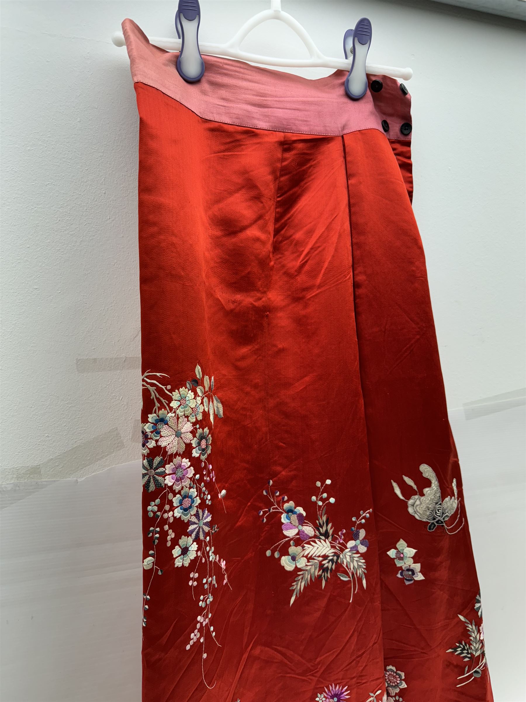 Early 20th century Chinese Han silk skirt, embroidered with flowers and butterflies, on a red ground, purchased from Liberty, London