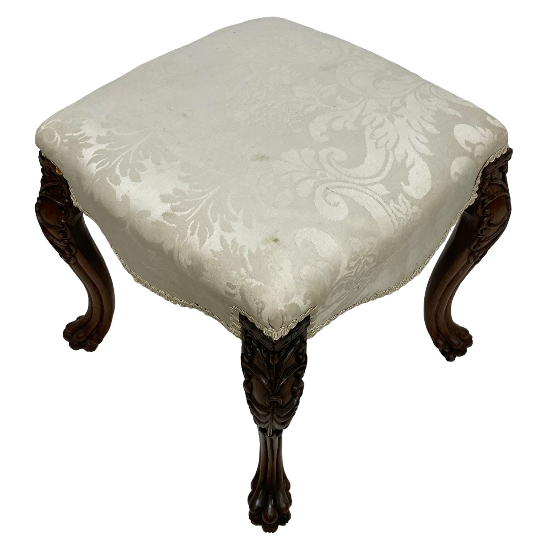 Georgian Irish mahogany dressing stool, overstuffed seat upholstered in in ivory damask fabric, the cabriole supports decorated with moulded interlacing scroll motifs with mycelium cap detail, over lobe carvings terminating to large paw feet