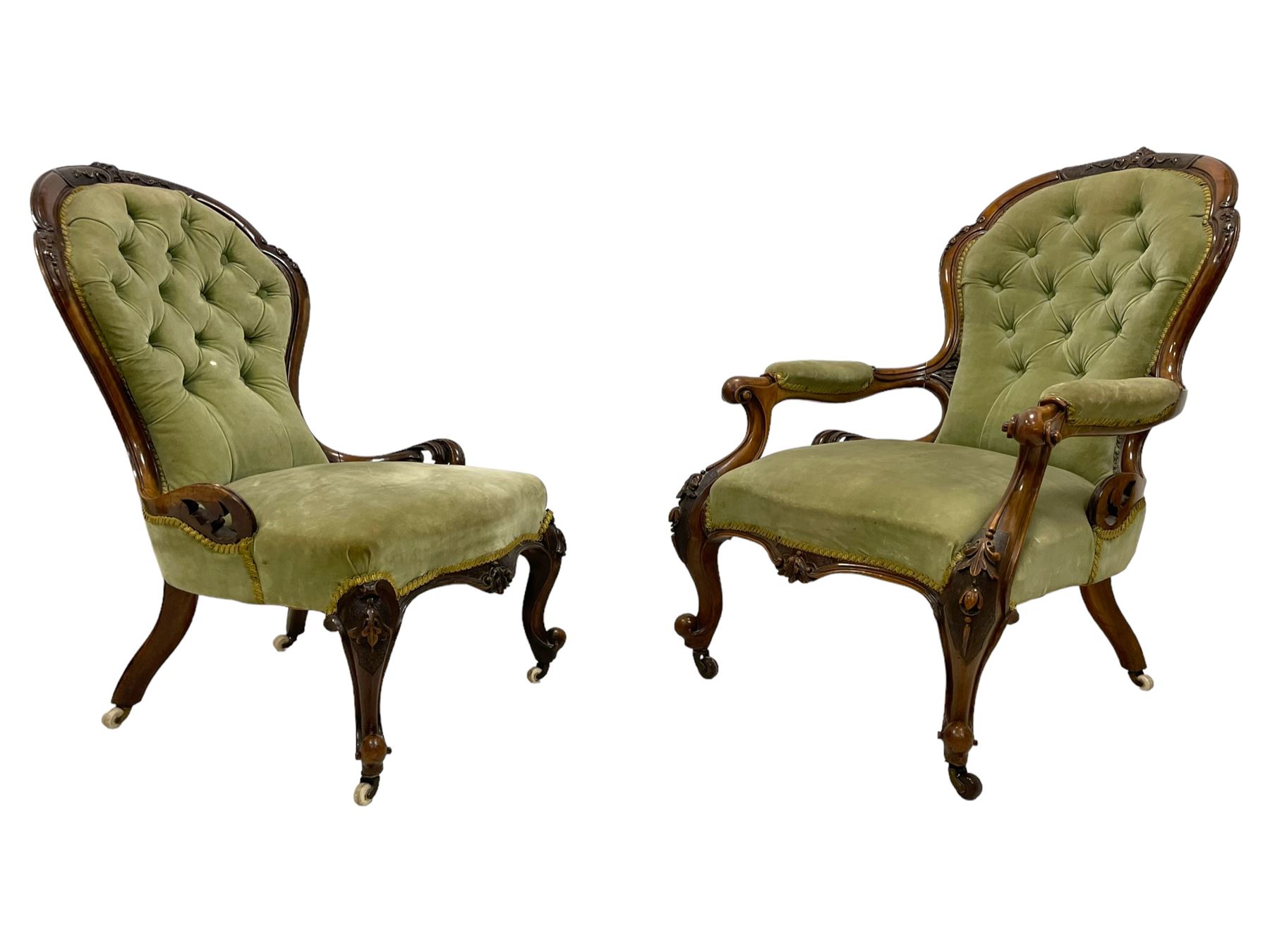 Pair of lady's and gentleman's Victorian carved walnut armchair and nursing chair, foliate carved cresting rail over shaped back with scrolled acanthus carved sides, the armchair with scroll arm terminals, the spoon back and sprung seat upholstered in buttoned sage green velvet, raised on cabriole supports with bell-flower moulded knees and scroll feet, on ceramic castors