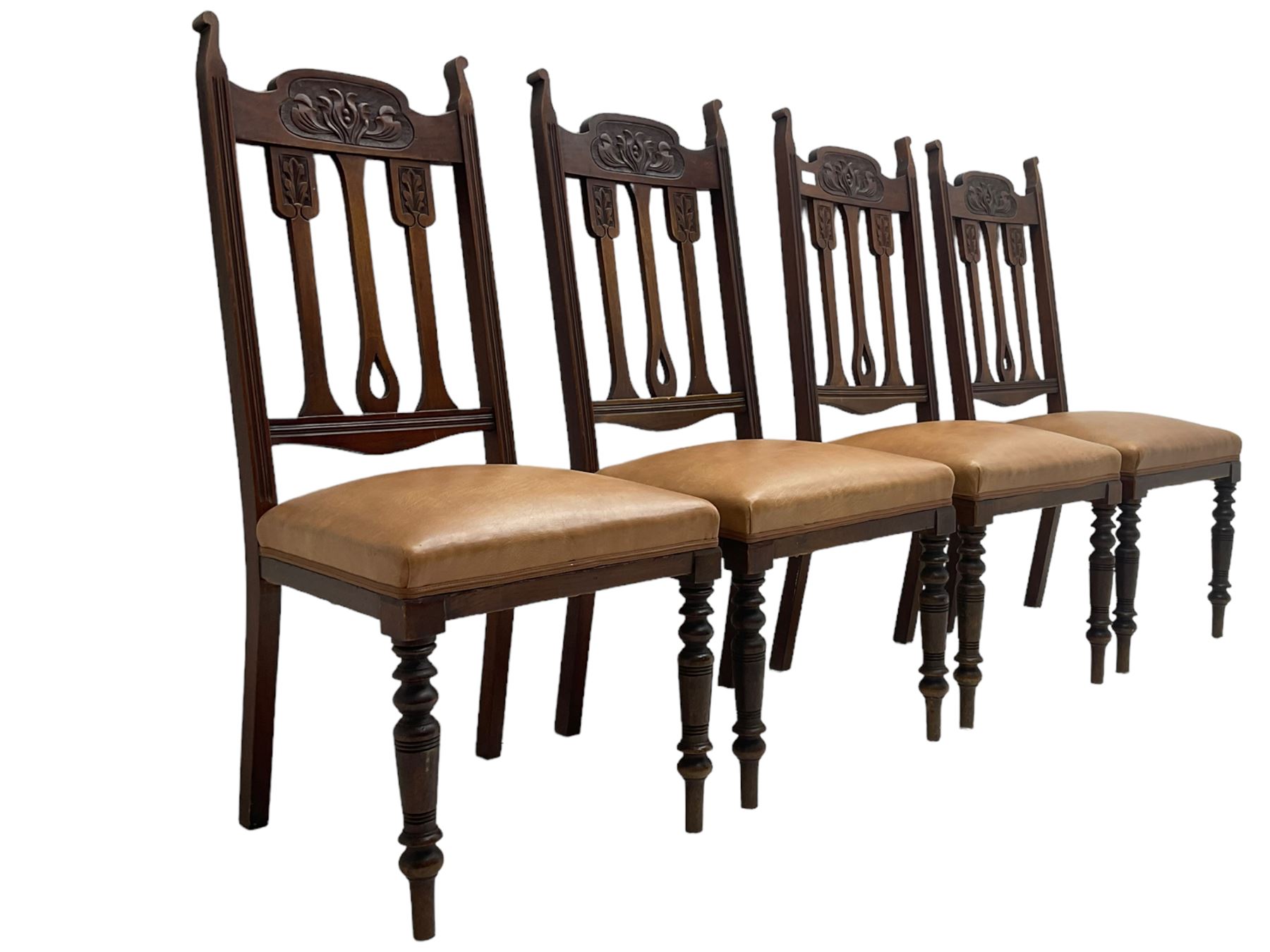 Set of four Edwardian walnut dining chairs, foliate carved high back over sprung seat upholstered in tan faux leather, raised on turned supports