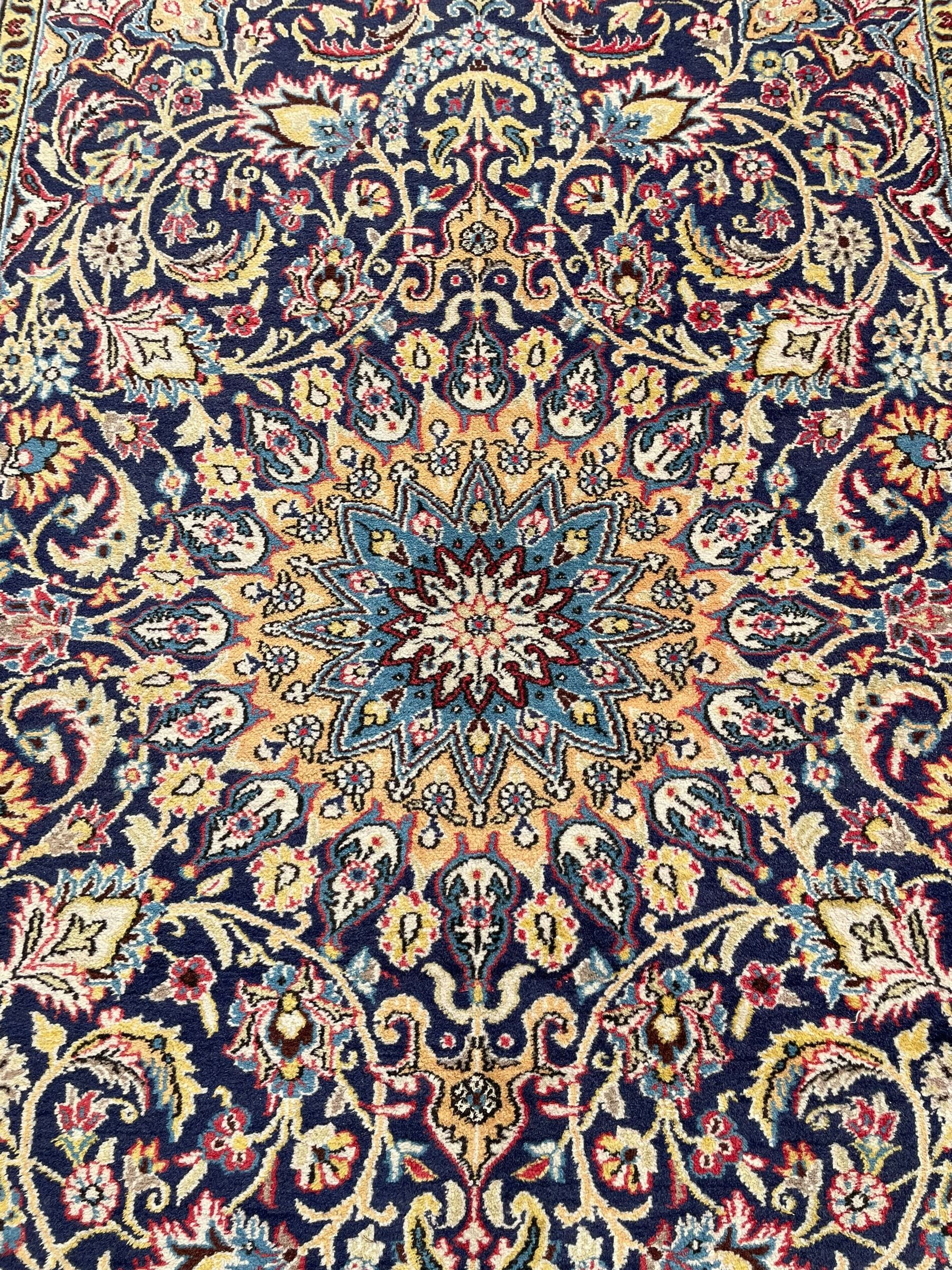 Persian indigo ground rug, overall arabesque design, central multi-point medallion surrounded by scrolling leafy branches and palmettes, the border decorated with repeating stylised plant motifs within guard stripes 