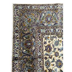 Persian Kashan ivory ground carpet, the busy field decorated with scrolling and interlaced leafy branches and palmettes, trailing branch border with repeating stylised plant motifs, within floral pattern guard stripes 