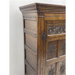 Large 18th century and later oak livery cupboard, the projecting dentil cornice over panelled front and two panelled doors, carved with scrolls and lozenges, the interior fitted with wooden hooks and showing signs of historic paint, panelled sides and boarded back, on shaped apron and bracket feet