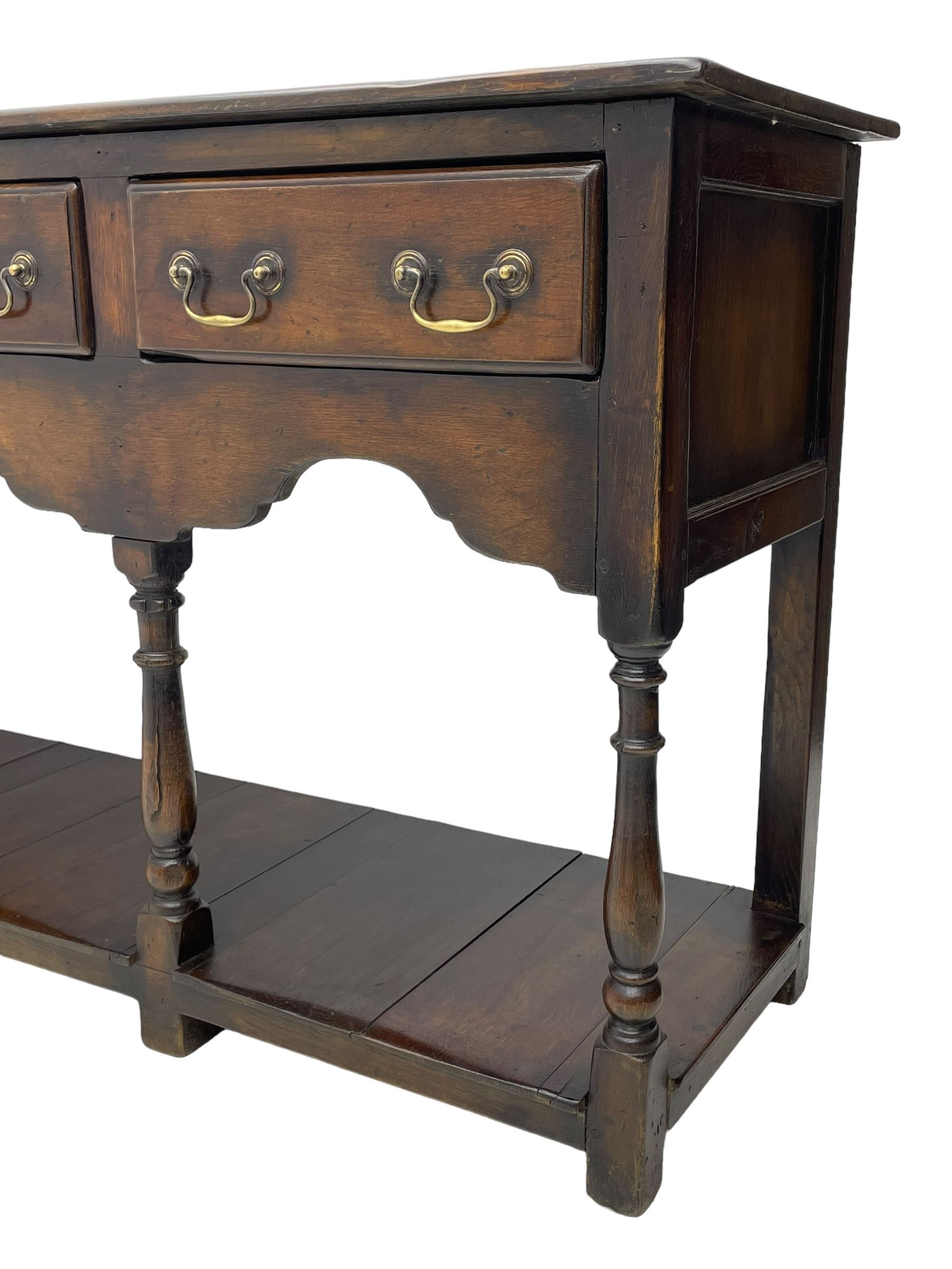 Georgian design oak dresser base, rectangular three plank top over three drawers and shaped apron, moulded drawer fronts with brass swan neck handles and circular plates, turned supports on panelled pot board base