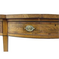 Large George III mahogany serpentine serving table, shaped top with crossing banding and stringing, the frieze fitted with three cock-beaded drawers, oval pressed brass handle plates decorated with urns, on square tapering supports with spade feet 