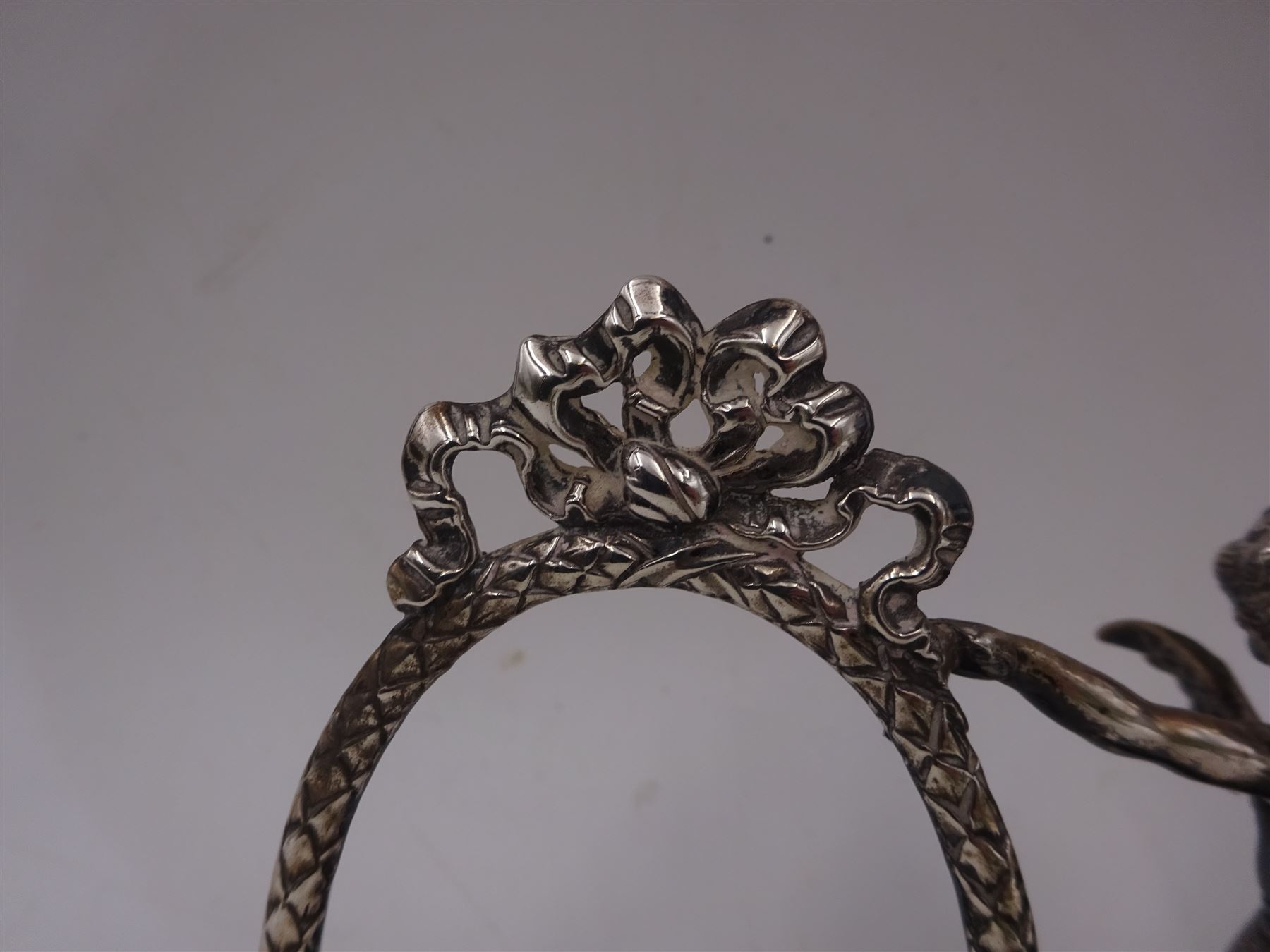 Edwardian silver double photograph frame by Berthold Herrman Muller, the oval frames each with ribbon surmount and supported by a central cherub, H8.5cm