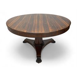 Mid-19th century rosewood breakfast or centre table, circular tilt-top on tapered barrel pedestal, concaved triangular platform, on carved paw feet with castors 