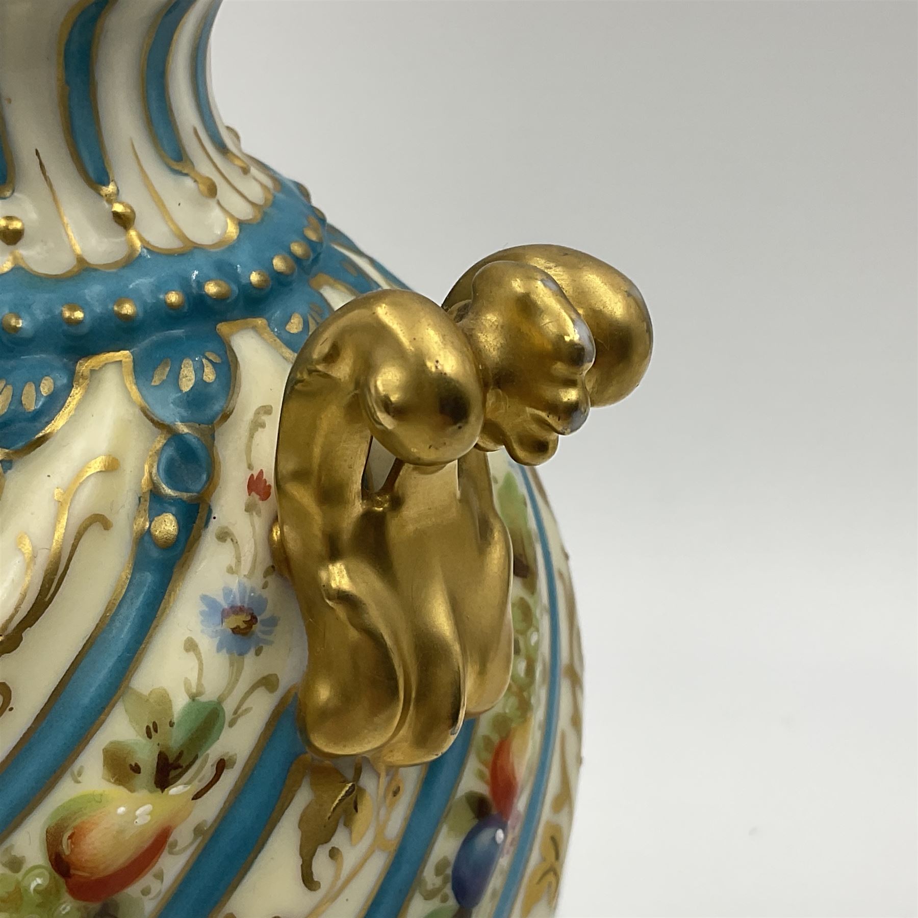 Pair of late 19th/early 20th century Sevres style vases and covers, of baluster form with gilt scroll handles and domed covers, the wrythen fluted bodies decorated with alternating bands of painted fruit and flowers and gilt vines, upon a white and celeste blue ground, with printed and impressed marks beneath, H22.5cm 