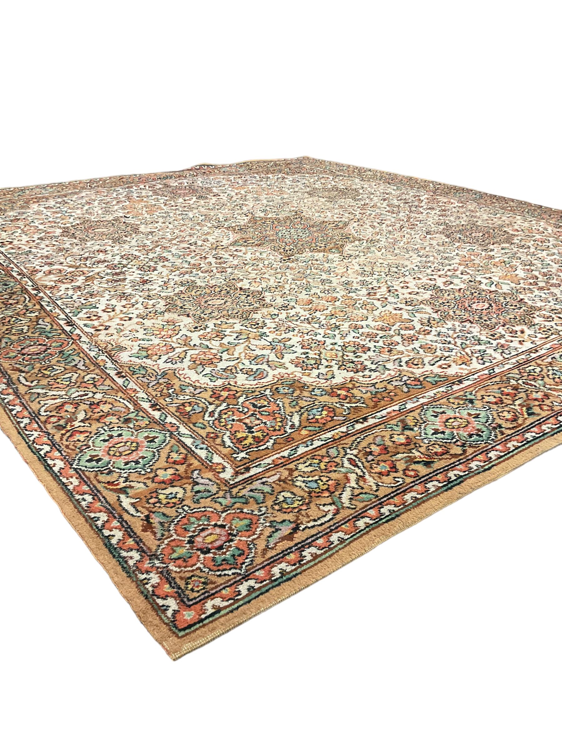 Large Persian design carpet, overall floral design, the field decorated with large rosette motifs surrounded by trailing foliate motifs, the border decorated with trailing branch and stylised plant motifs