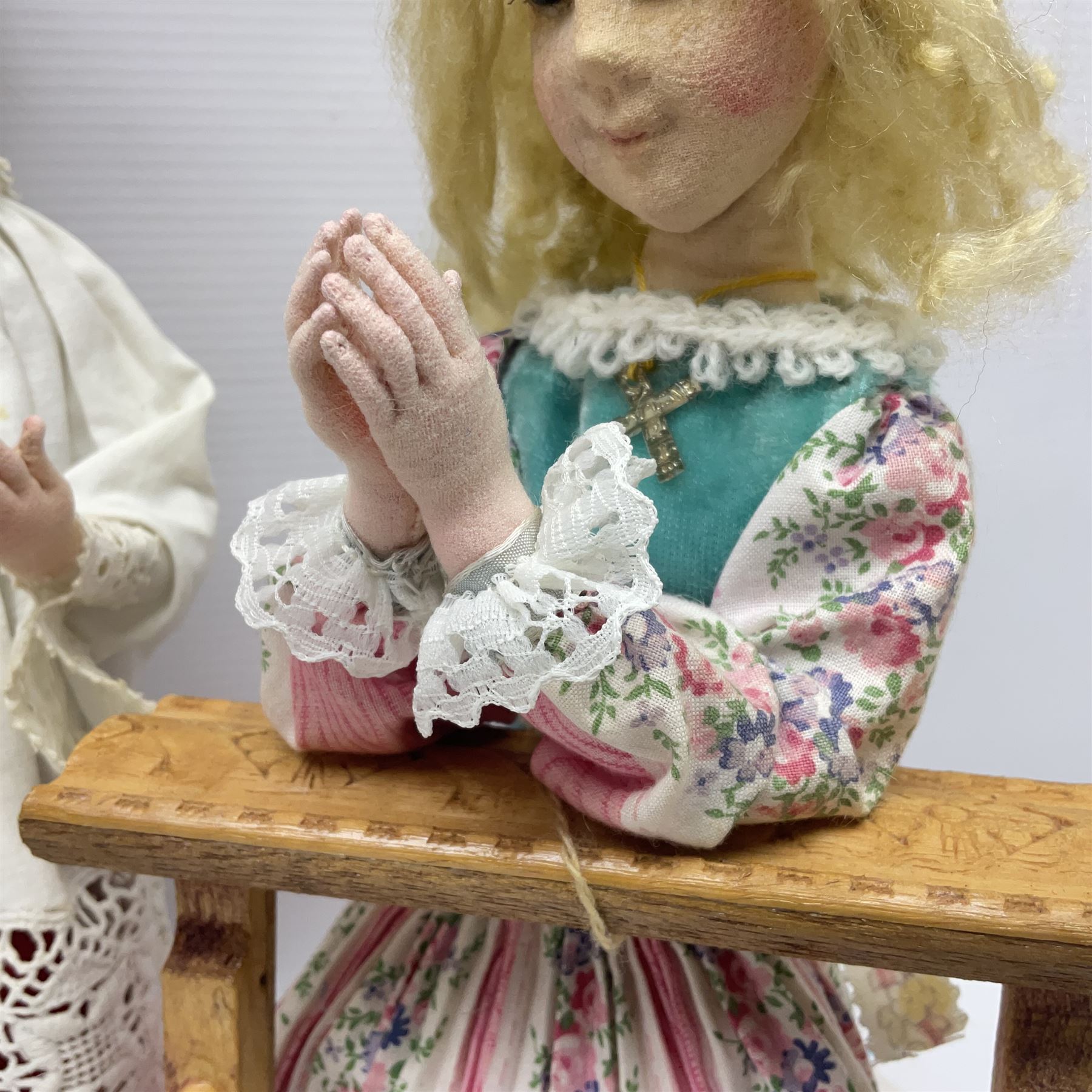 Anna Meszaros Hungary - two hand made needlework figurines, each of a young girl kneeling by an alter rail praying H28cm; together with another similar of a chorister H29cm (3)  Auctioneer's Note: Anna Meszaros came to England from her native Hungary in 1959 to marry an English businessman she met while demonstrating her art at the 1958 Brussels Exhibition. Shortly before she left for England she was awarded the title of Folk Artist Master by the Hungarian Government. Anna was a gifted painter of mainly portraits and sculptress before starting to make her figurines which are completely hand made and unique, each with a character and expression of its own. The hands, feet and face are sculptured by layering the material and pulling the features into place with needle and thread. She died in Hull in 1998.