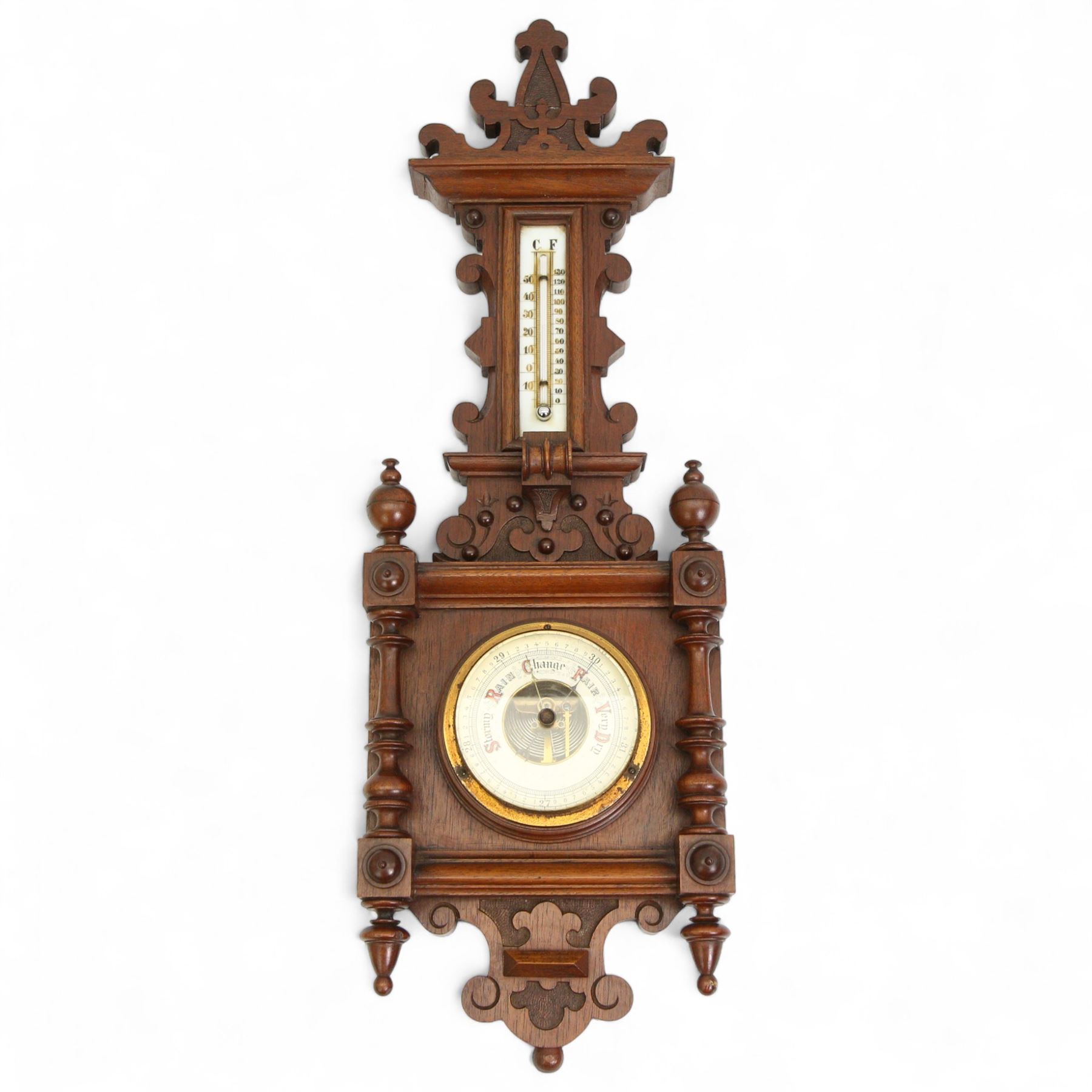 Early 20th century Edwardian aneroid barometer, in a mahogany case with scroll carving, turned finials and pendants, boxed mercury thermometer recording temperature in degrees Fahrenheit and centigrade on opaline register, open dial barometric register with gothic script predictions, steel indicating hand and brass recording hand.