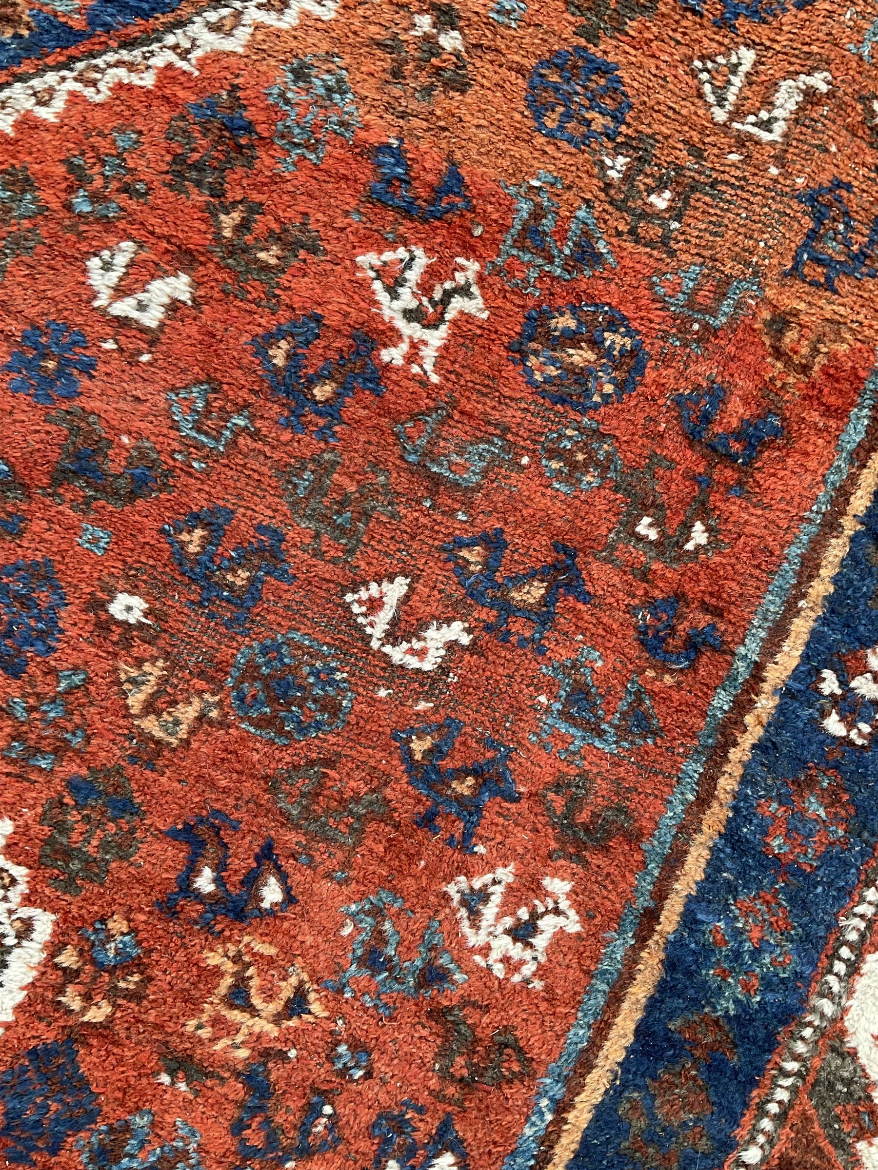 Persian Shiraz crimson ground rug, three connected lozenge medallions on a field decorated with small bird motifs, the main border decorated with repeating geometric motifs, within hooked guard stripes 