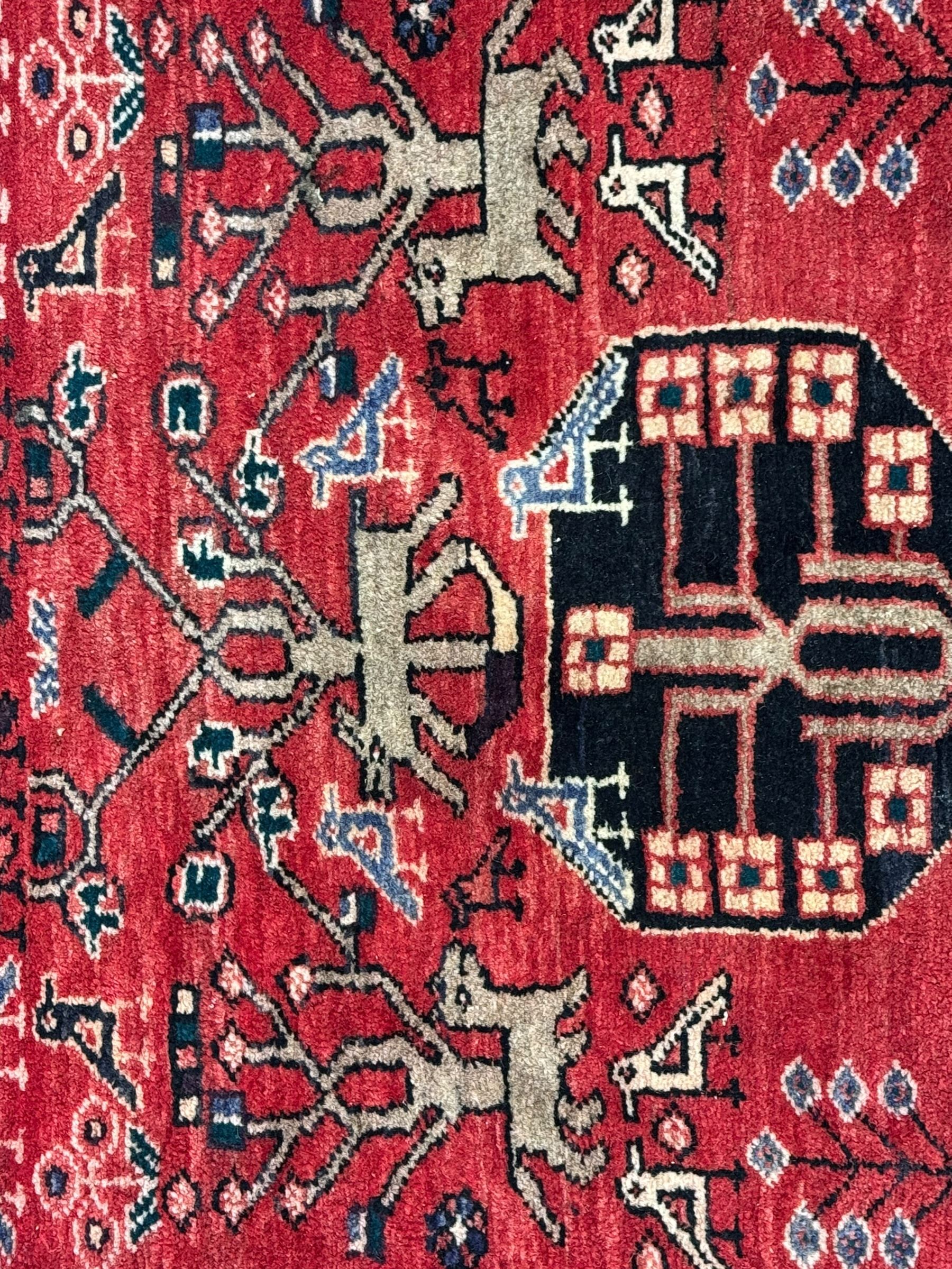 Persian crimson ground runner, the field decorated with stylised tree and animal motifs, indigo ground border decorated with alternating stylised flowerhead and bird motifs 