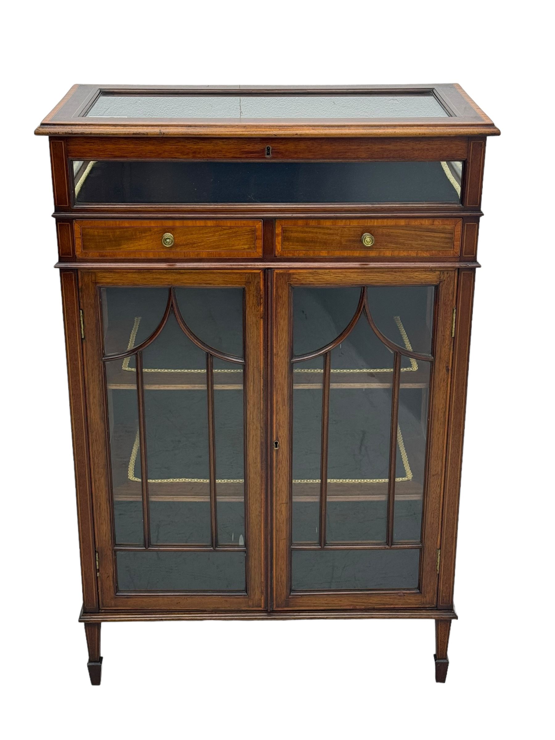 Edwardian mahogany bijouterie display cabinet, featuring satinwood inlay and crossbanding, hinged glazed top fitted with two banded drawers, over two astragal glazed doors enclosing black wool baize lined shelves with gold trim, supported by spade feet