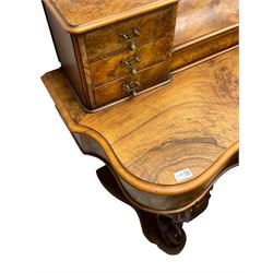 19th century figured walnut dressing table, the raised bevelled mirror back in carved foliage frame with scrolled terminals, fitted with central hinged compartment flanked by small trinket drawers, serpentine moulded top over single frieze drawer, on cabriole supports united by a platform base