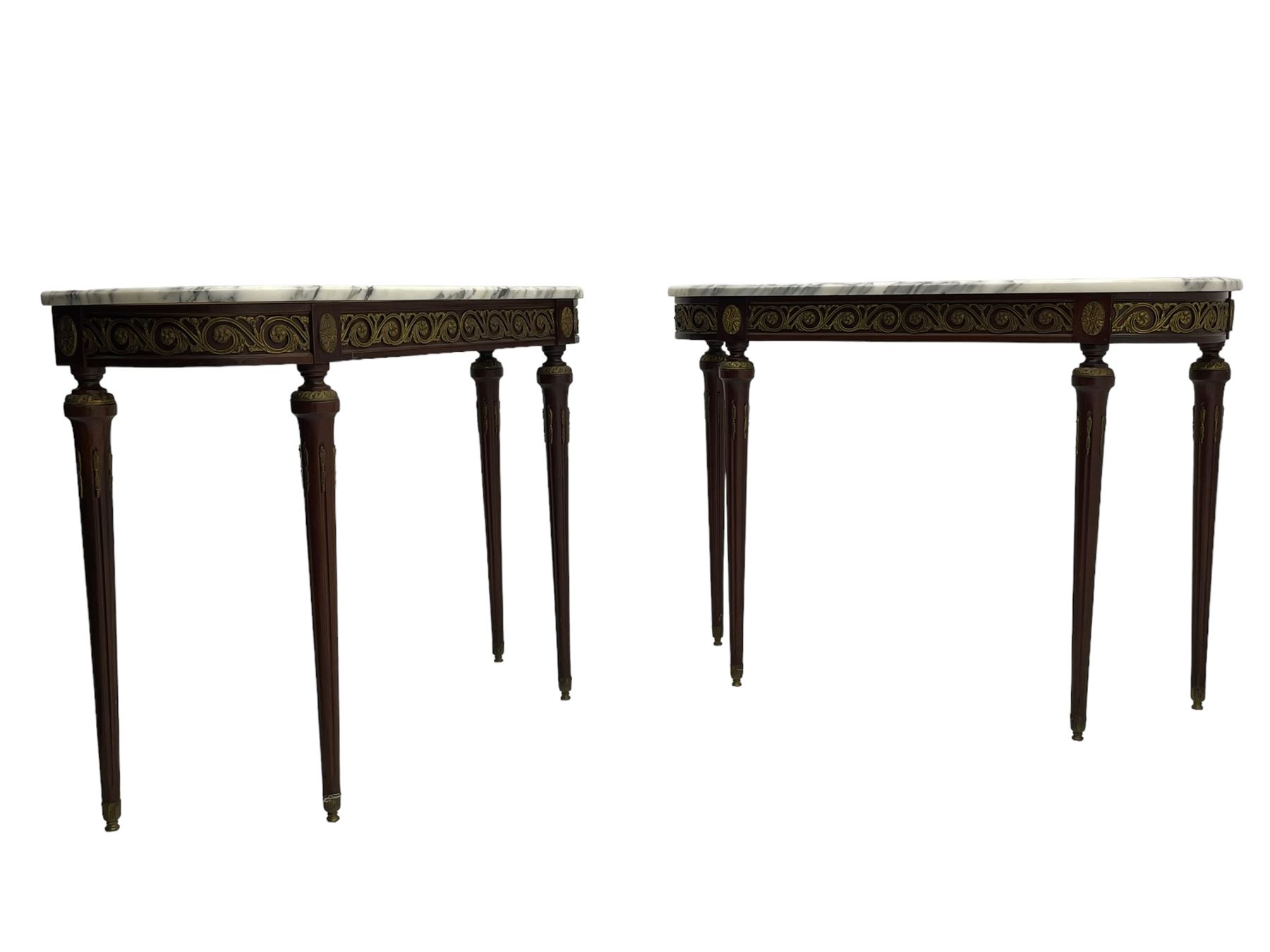 Pair of late 20th century French design mahogany console tables, D-end form with white and grey veined marble tops, the frieze rails decorated with scrolled leaf and flower head cast brass mounts, on turned and fluted supports with cast brass mounts and feet 