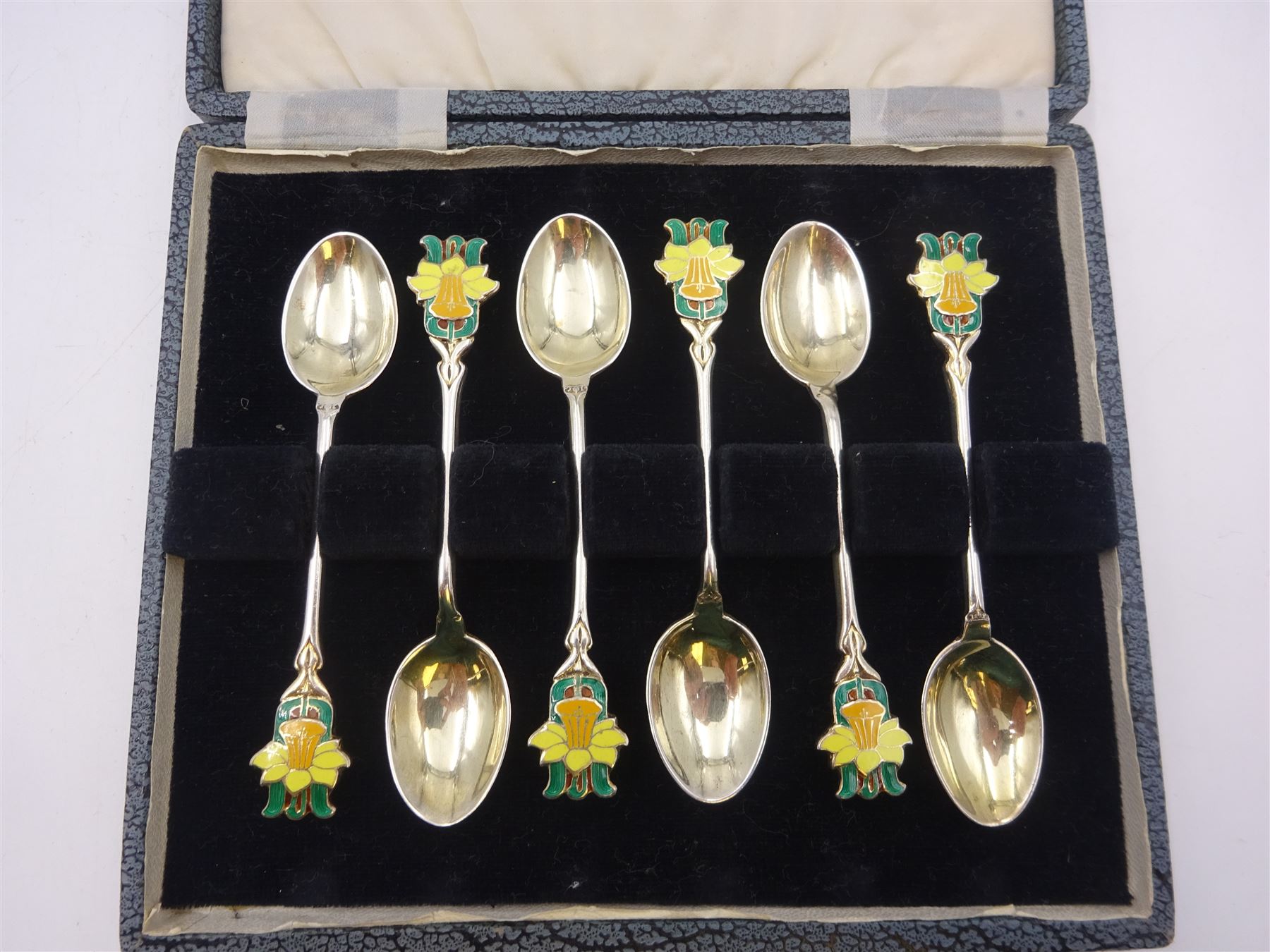 Set of six silver coffee spoons, each with enamelled daffodil decoration to terminal, hallmarked Turner & Simpson Ltd, Birmingham 1938, contained within fitted case