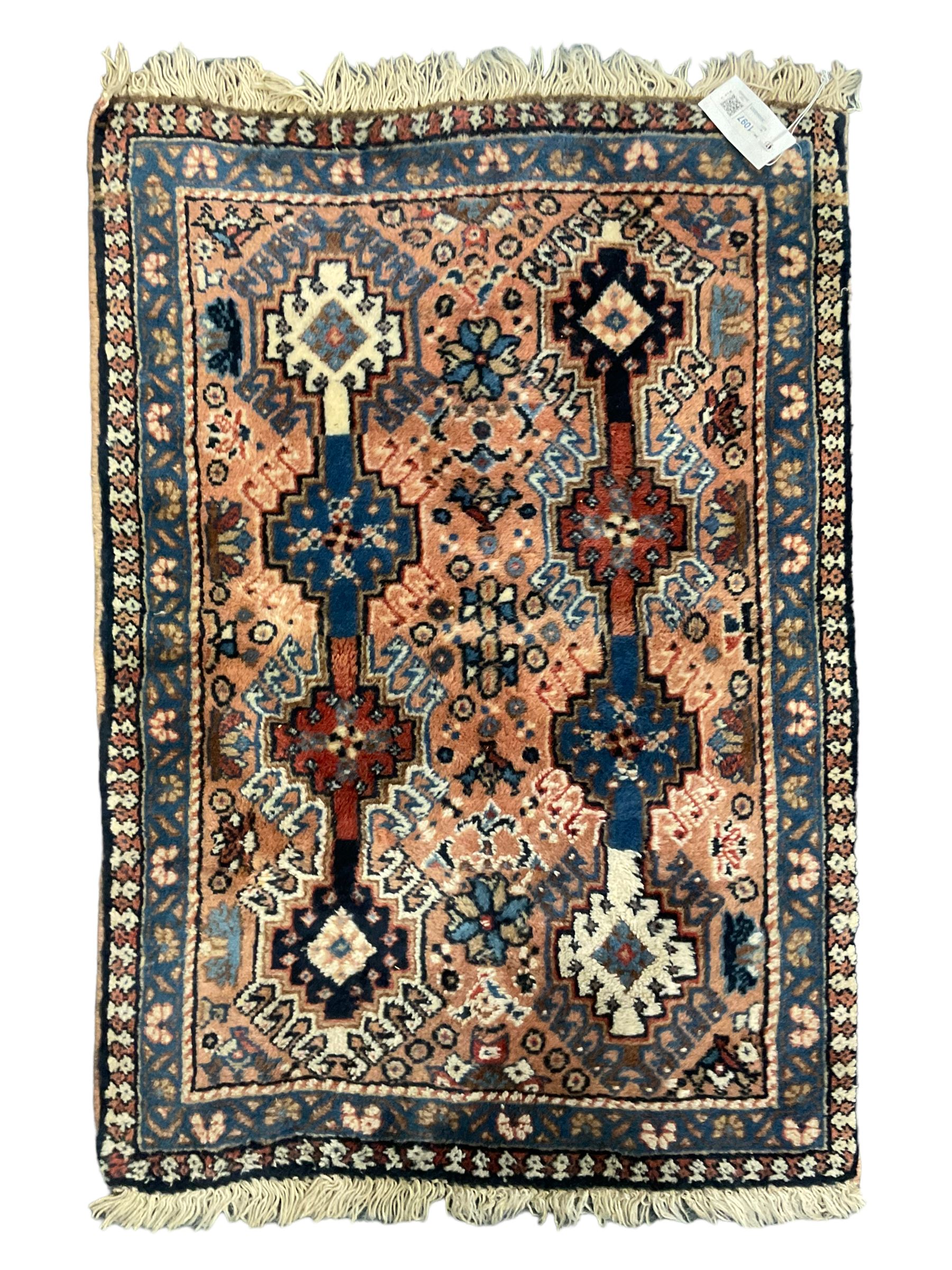 Persian prayer purple ground, decorated with three pointed buildings over tailing lozenge patterned field (111cm x 82cm); and a small Persian rug or mat, overall geometric design (81cm x 56cm)