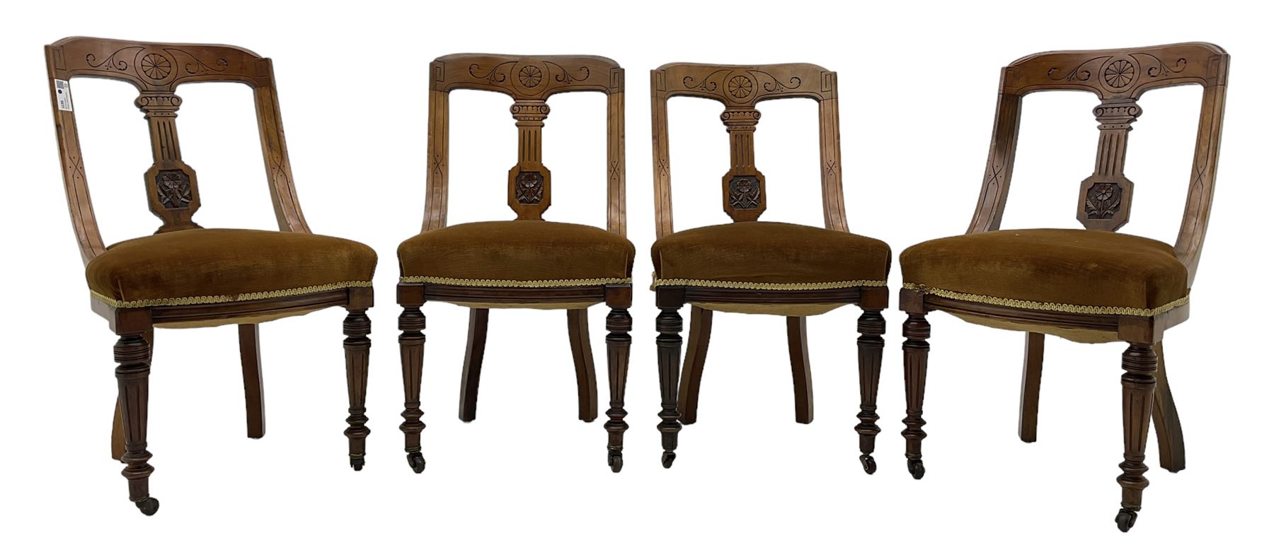 Set of four late Victorian walnut dining chairs, carved with stylised floral decoration and scrolling branches, upholstered seat, on turned and fluted supports 