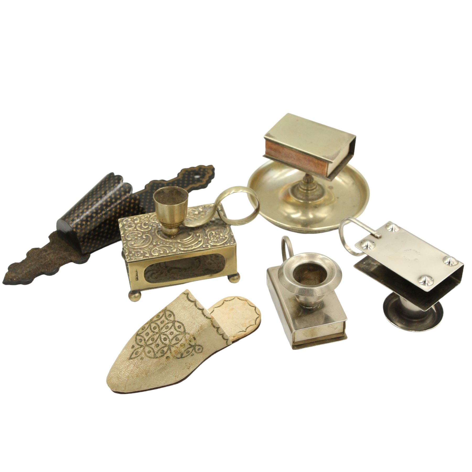 Three Victorian and later silver-plated combination matchbox holders/ candlesticks, a silver-plated combination matchbox holder and ashtray, an early 20th century papier mache wall pocket with striker and a leather matchbox holder in the form of a slipper (6)