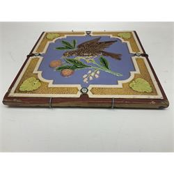 19th century Minton & Co majolica tile, decorated in relief with a bird upon a fruiting branch against a blue ground, with textured ochre border and anthemion to each corner, impressed mark verso, H19.7cm