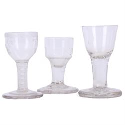 Three 18th century drinking glasses, the first example with rounded bowl engraved with foliate sprigs and border to rim, upon a short double series opaque twist stem and thick foot, H10cm the second with ogee part fluted bowl upon a short plain stem and thick stepped foot, H9cm, and the third toastmaster example with rounded funnel bowl upon a plain stem and thick firing foot, H11cm 