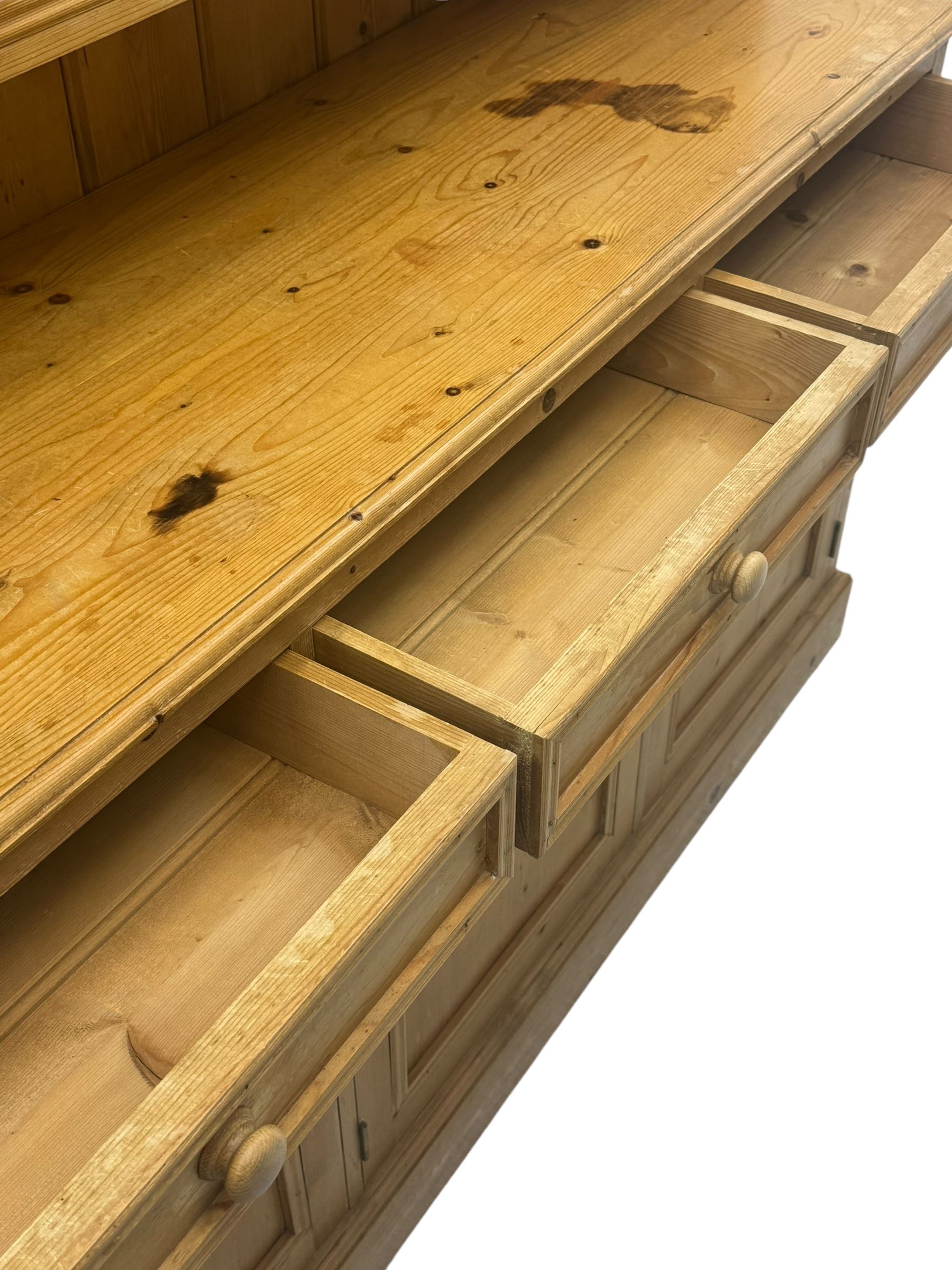 Traditional design waxed pine dresser, upper section with moulded cornice over scalloped frieze, fitted with two open shelves and four drawers, lower section with three drawers over three panelled cupboards, on plinth base