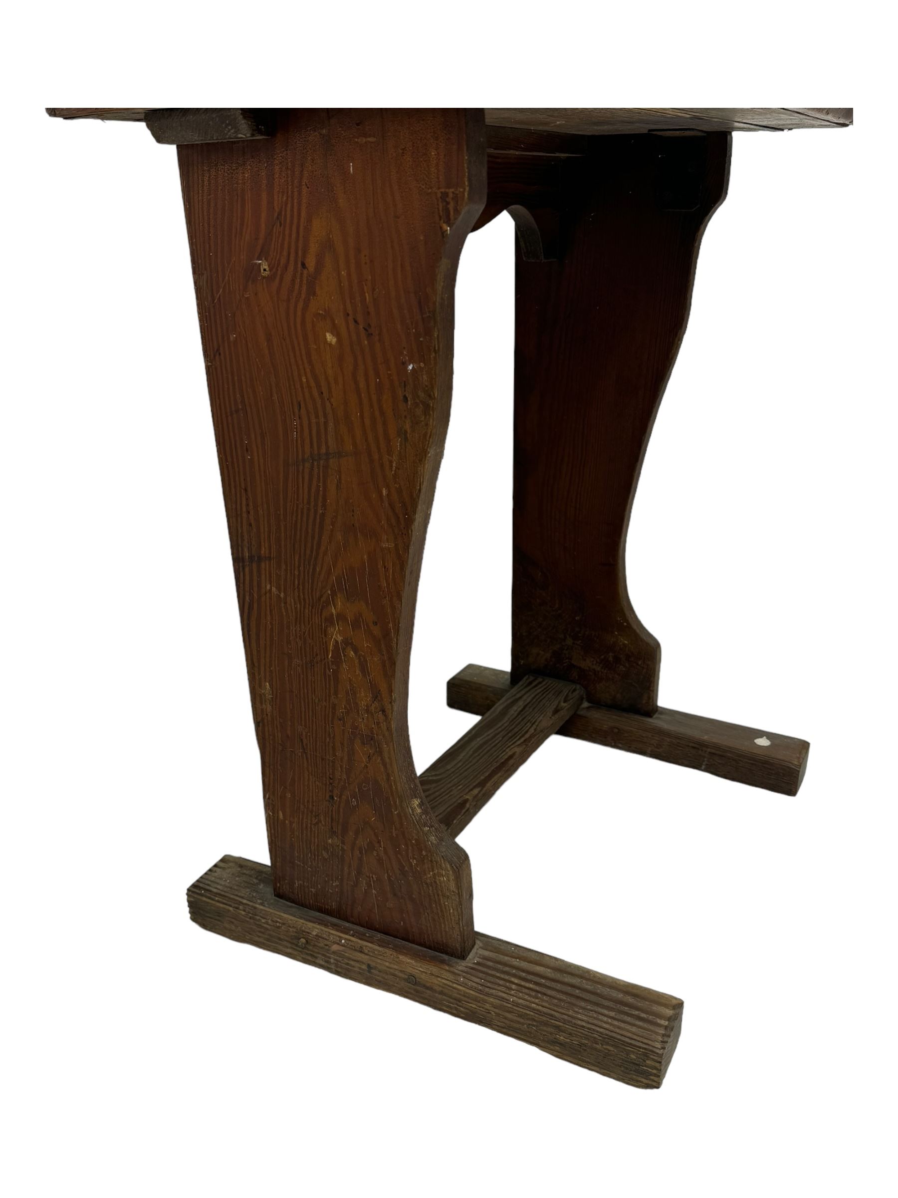 Three pitch pine school desks, each with rectangular lift-top with recessed ink well enclosing storage compartment, on trestle supports joined by stretcher