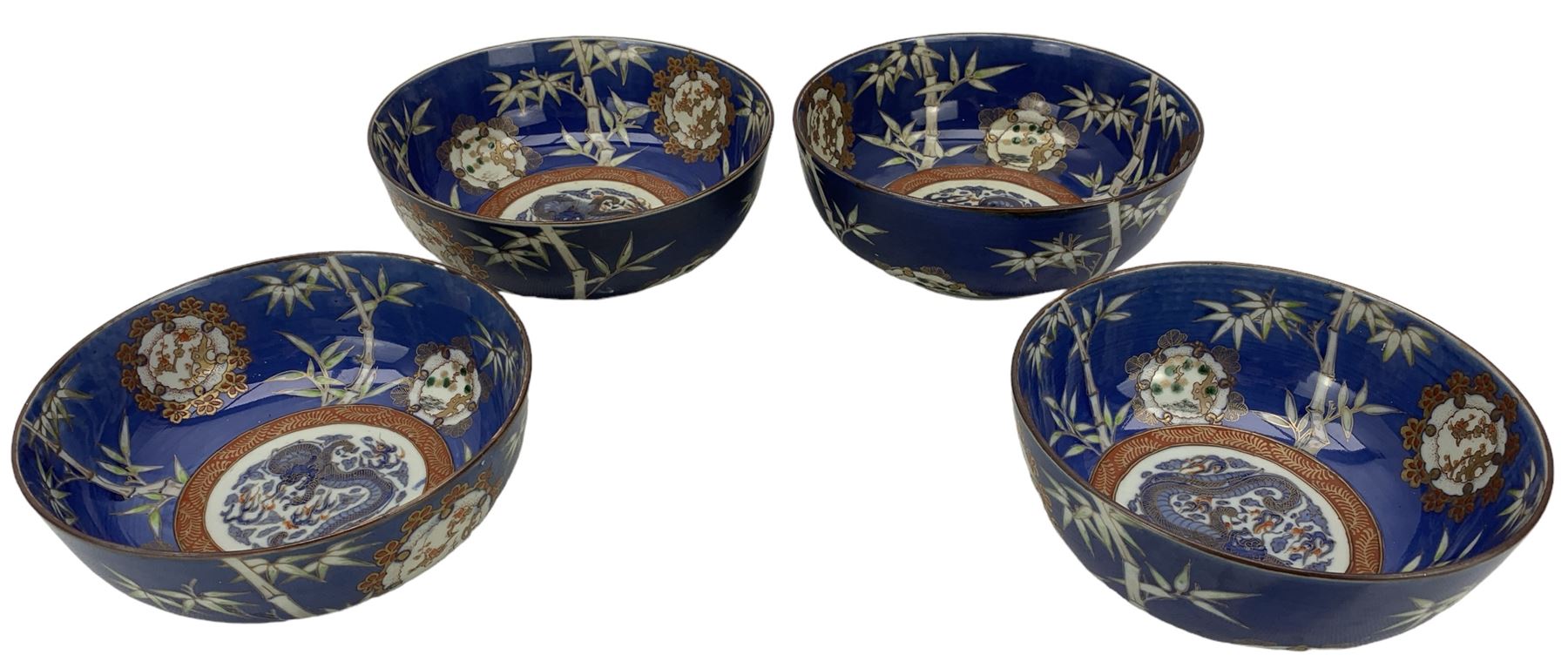 Set of four Japanese graduating porcelain bowls, each centrally painted with a coiled dragon in reserves, bamboo and foliate roundels against a blue ground, largest measuring D24.5cm (4)