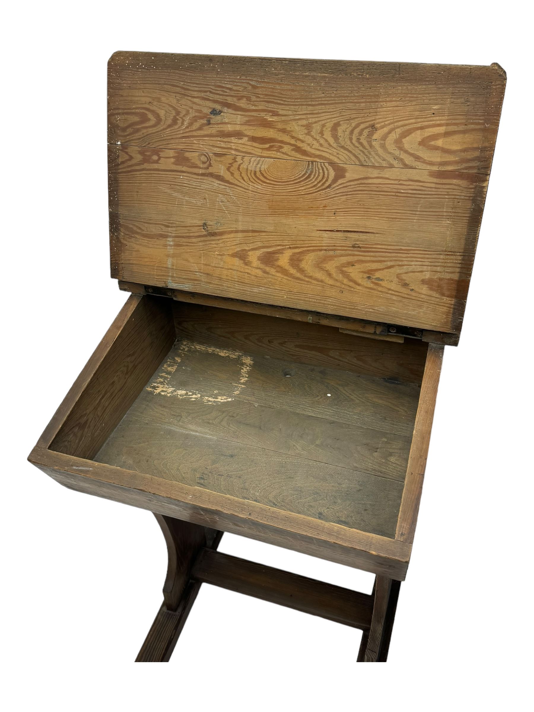 Three pitch pine school desks, each with rectangular lift-top with recessed ink well enclosing storage compartment, on trestle supports joined by stretcher